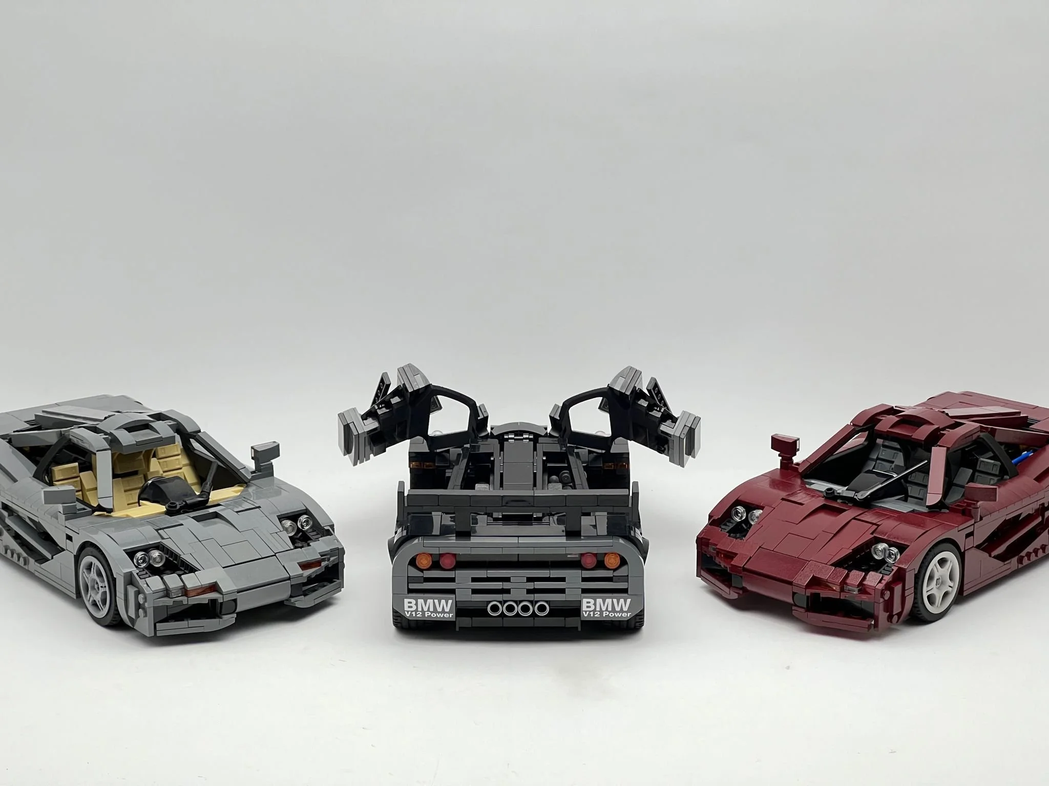 Three LEGO supercars: silver sports car, a black race car with rear wing, and a red sports car, all displayed on a white background.