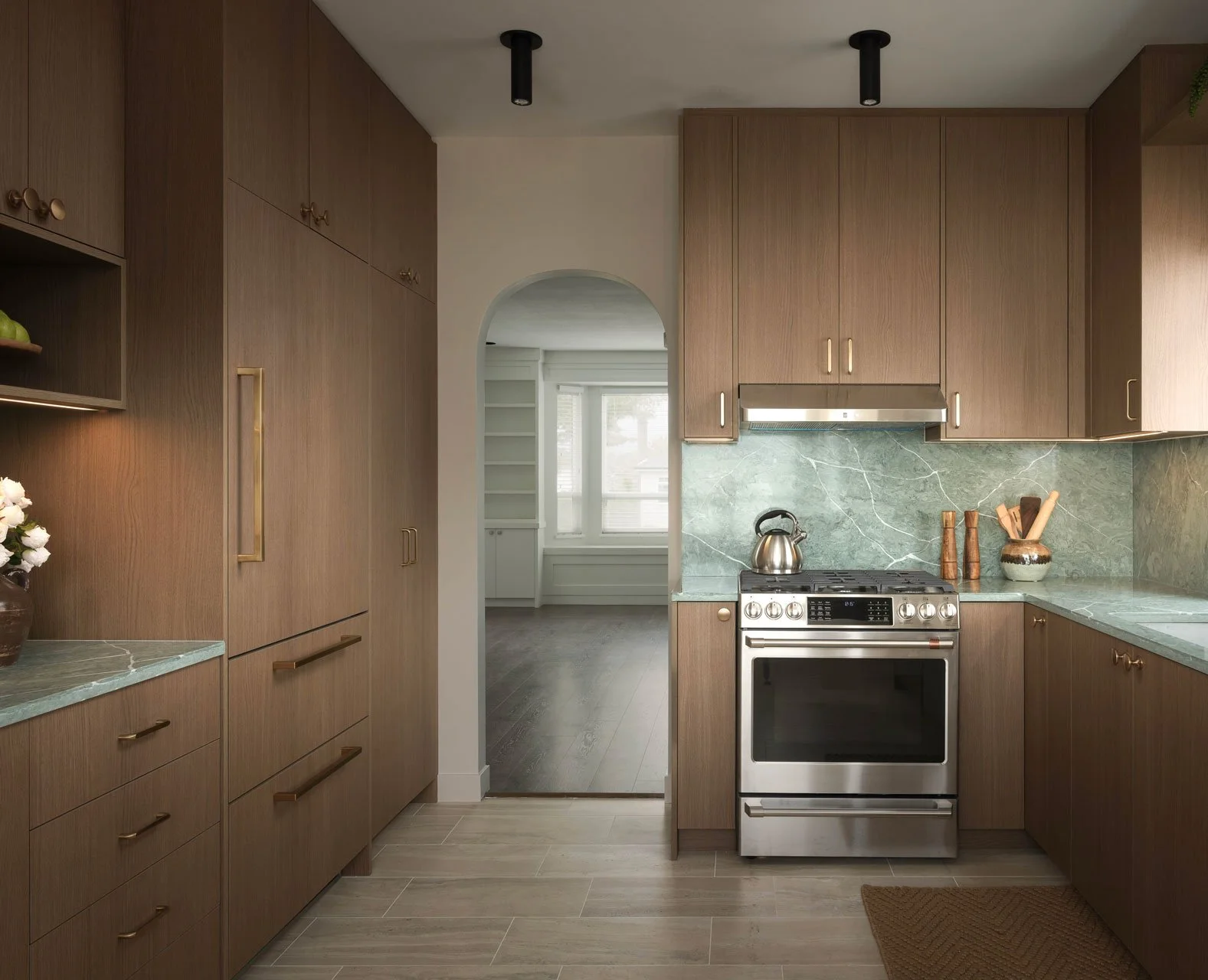 East Vancouver Kitchen Renovation With Arched Doorway, Integrated Appliances, Gold Hardware, and Green Marble Slab Countertop and Backsplash