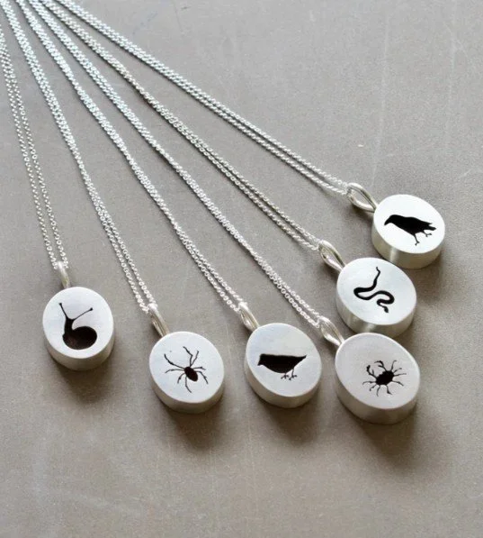 Many handmade sterling silver necklaces with animal silhouettes.