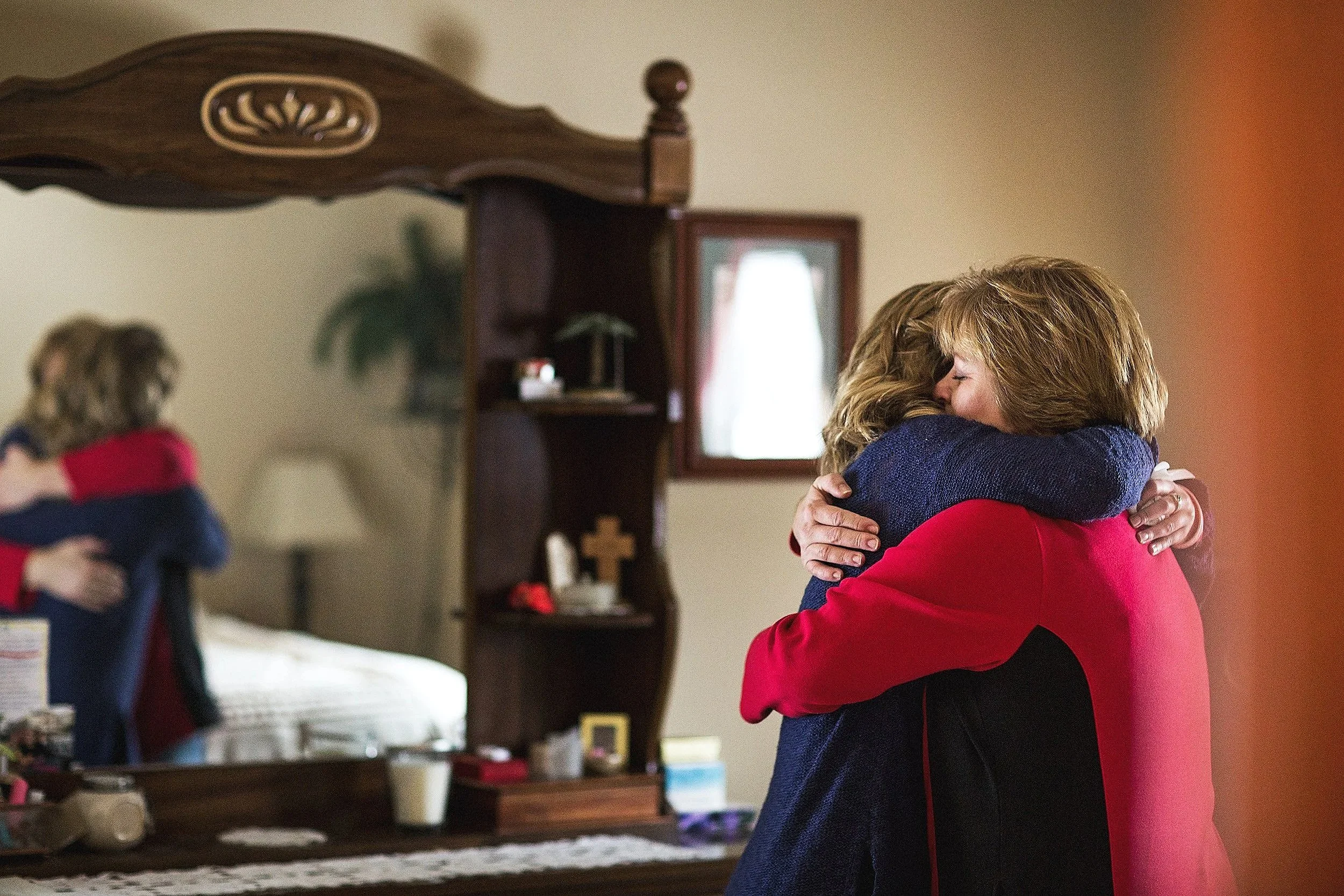 A cancer survivor embraces a loved one in a bedroom, reflecting support and healing during the St. Michael’s Foundation campaign.