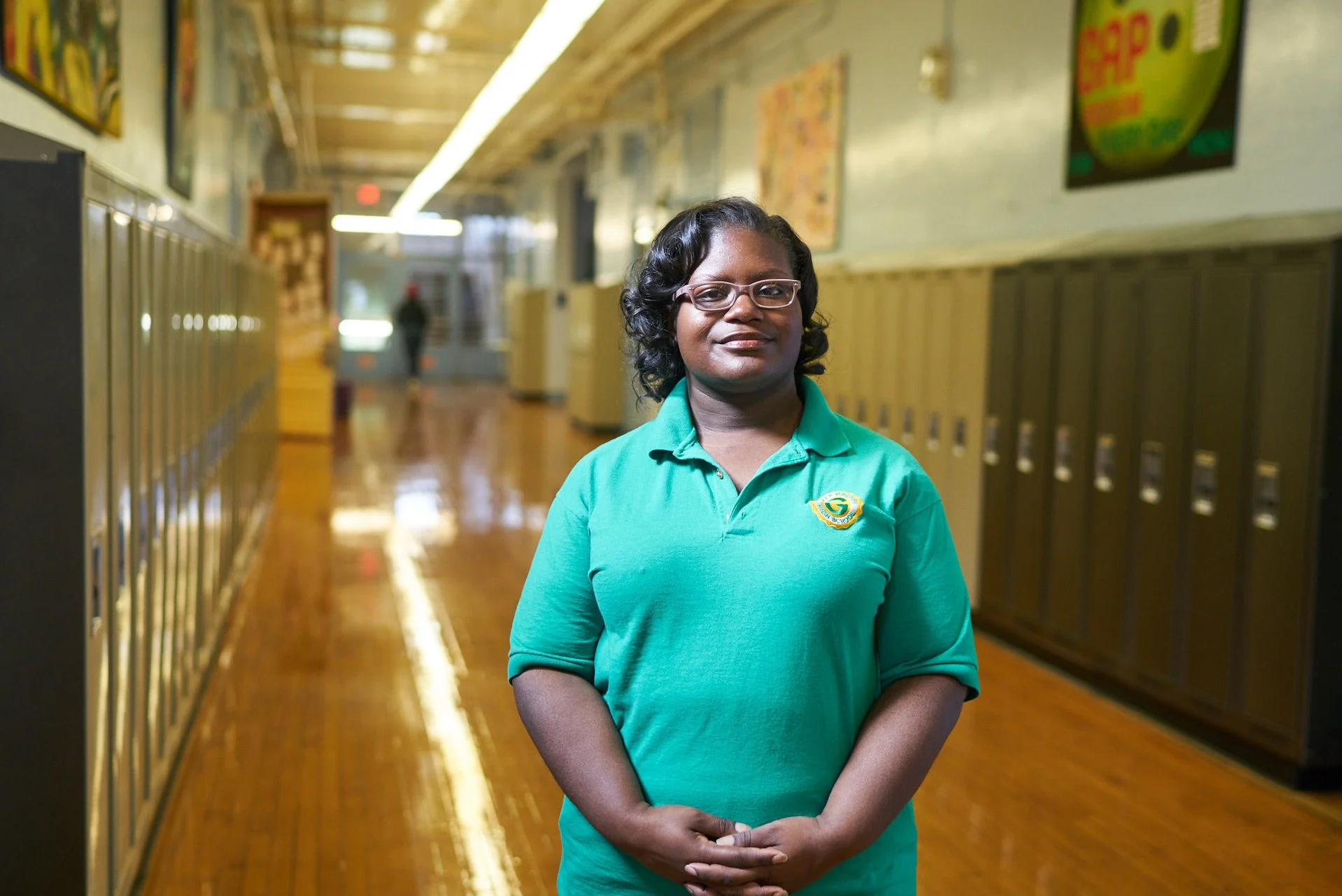 School staff member standing in a hallway lined with lockers during a nonprofit education program.