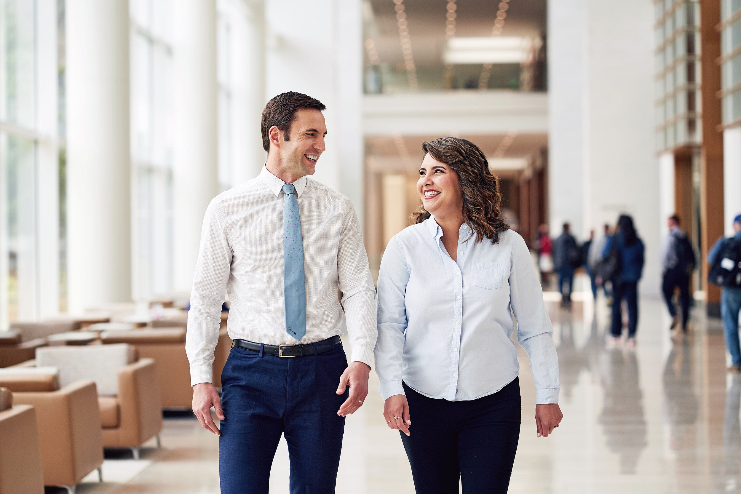Two business professionals walking. and talking in a modern corporate atrium