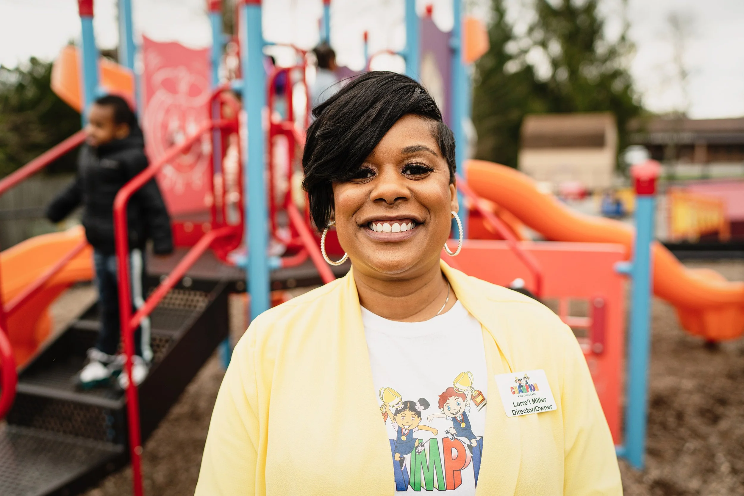 Program director standing in front of a playground at a community childcare center.