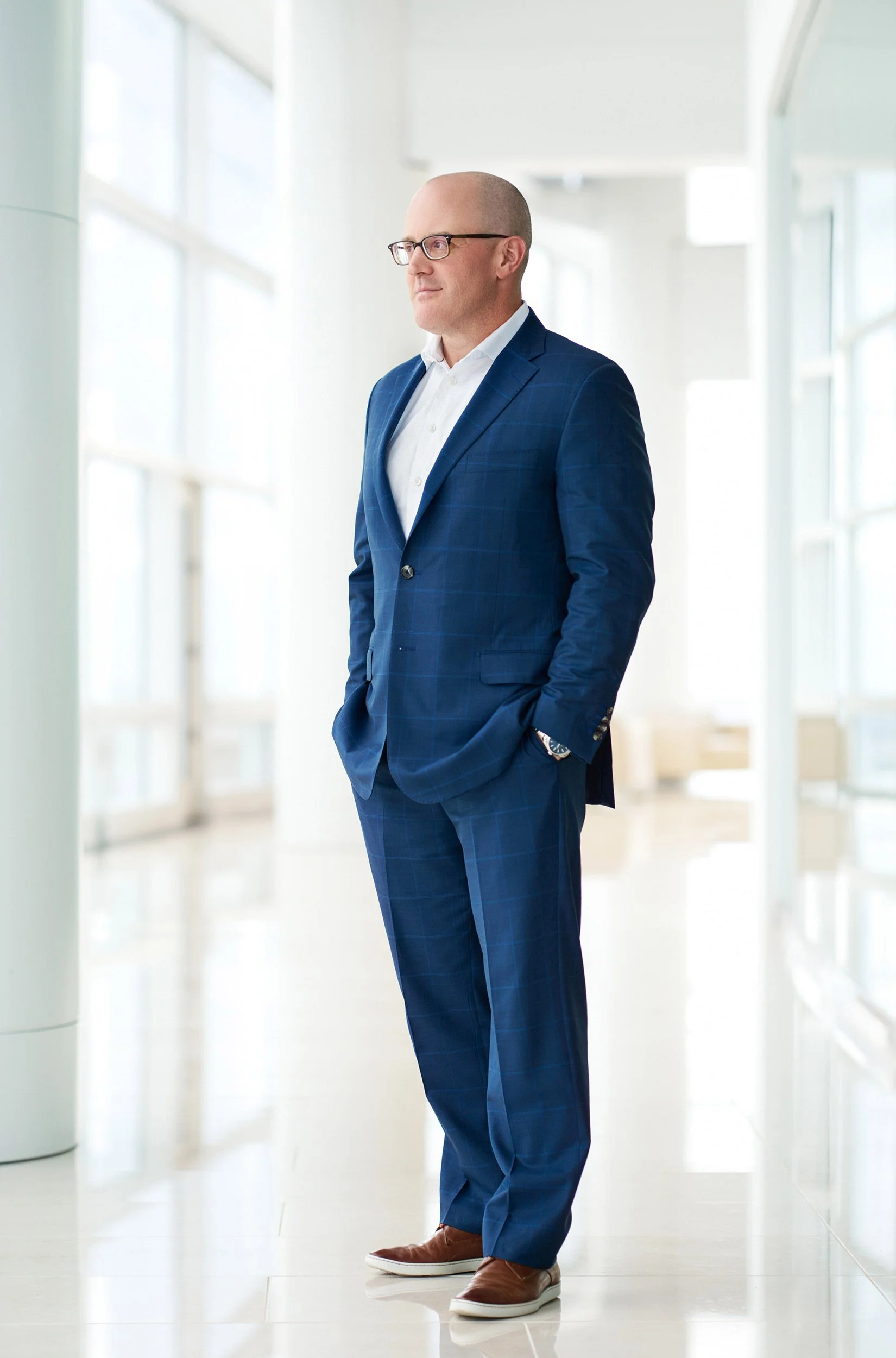Full-length executive portrait of a business leader in a blue suit in a bright modern atrium