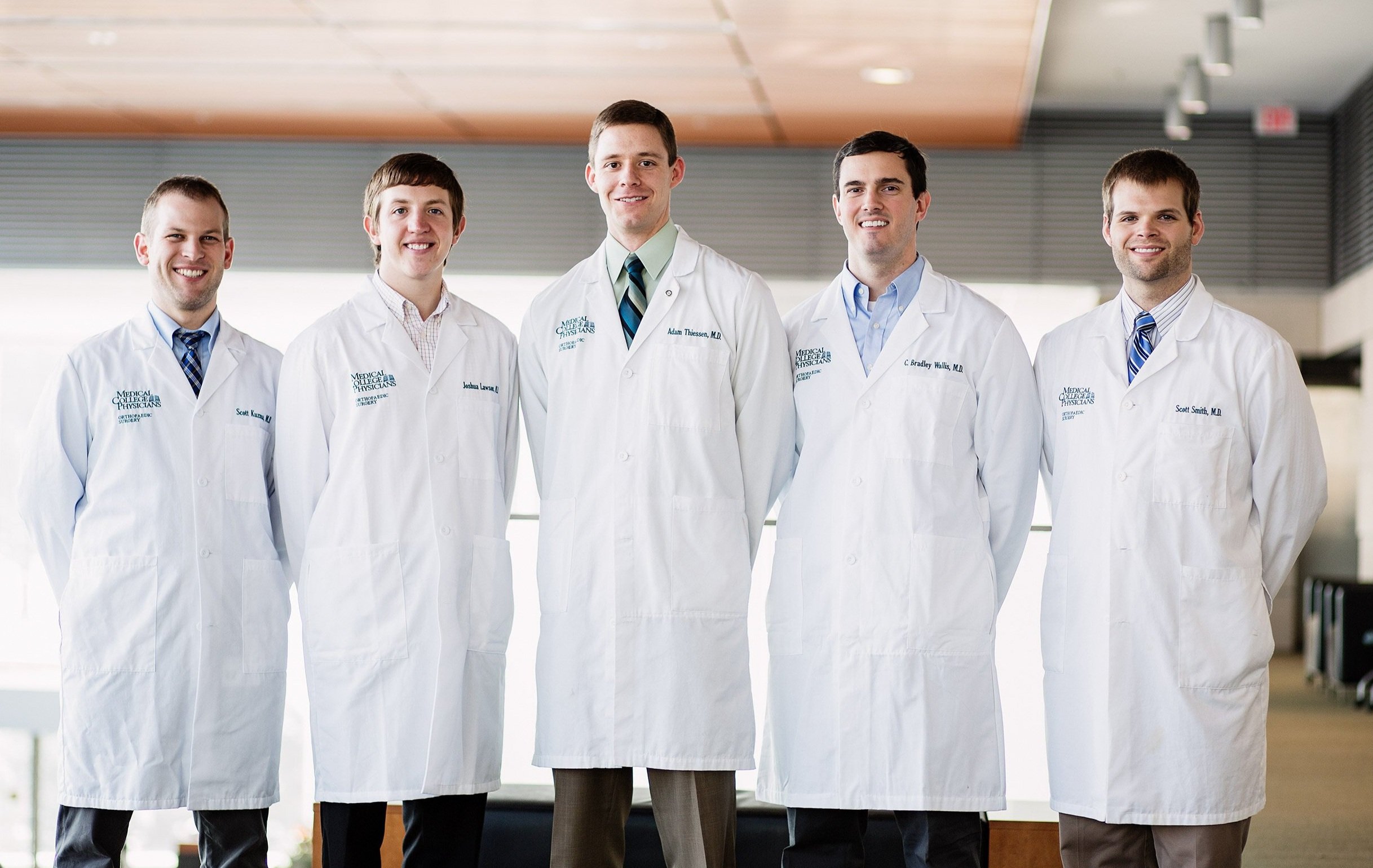 Group of hospital physicians in white coats standing together in a medical facility.