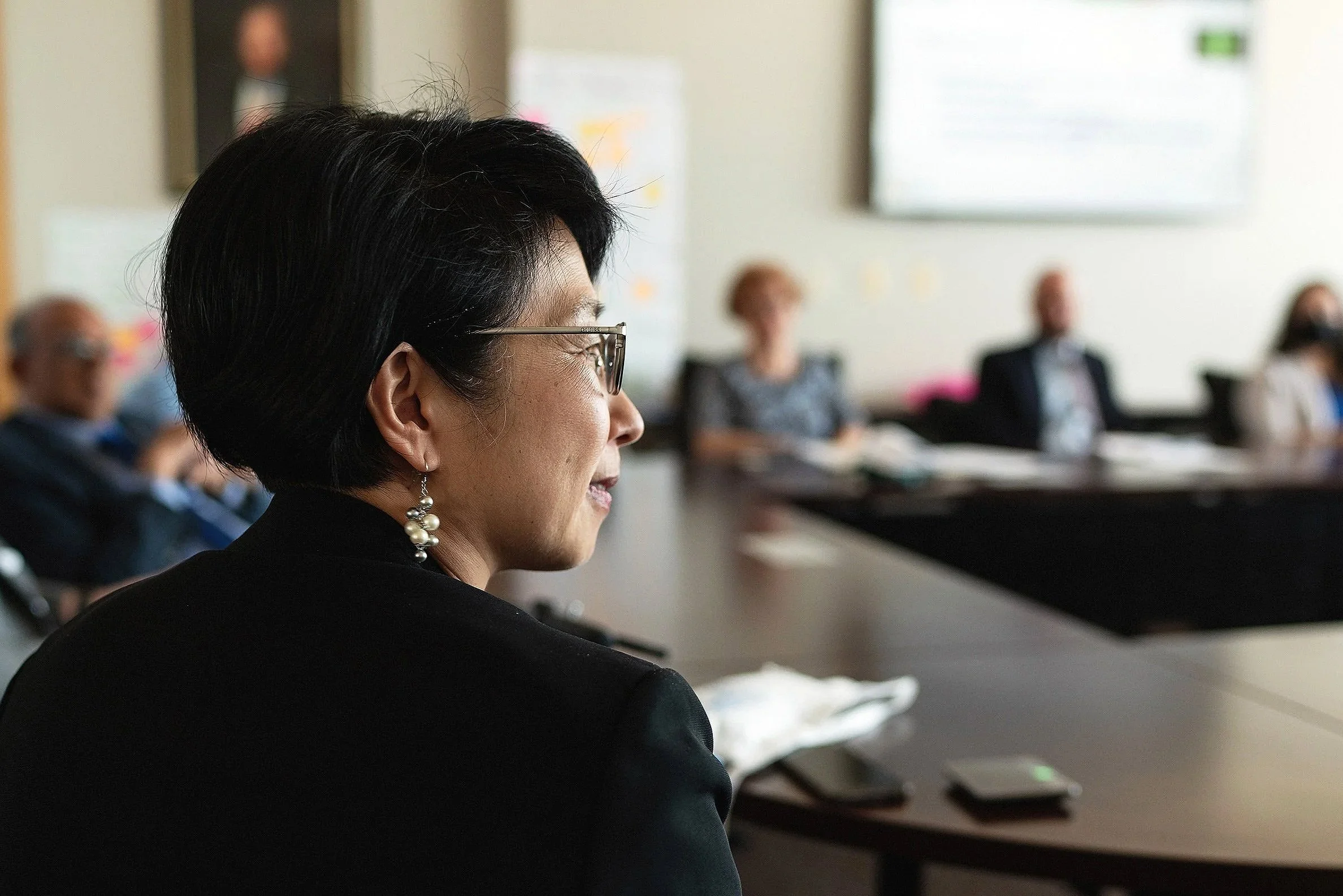 Executive leadership portrait of female business professional speaking during corporate board meeting.