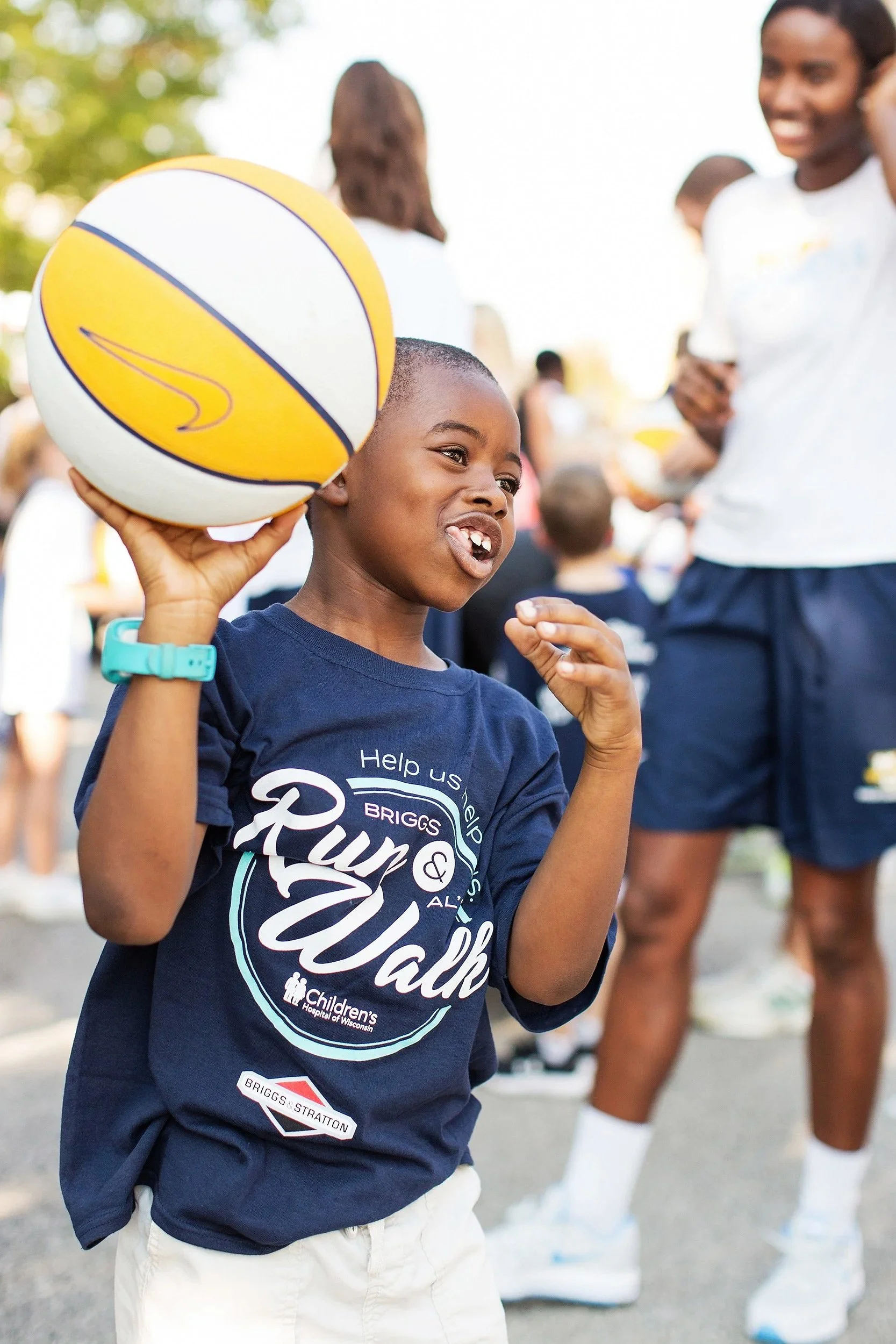 Smiling child holding a basketball at an ALS Run & Walk community fundraising event.