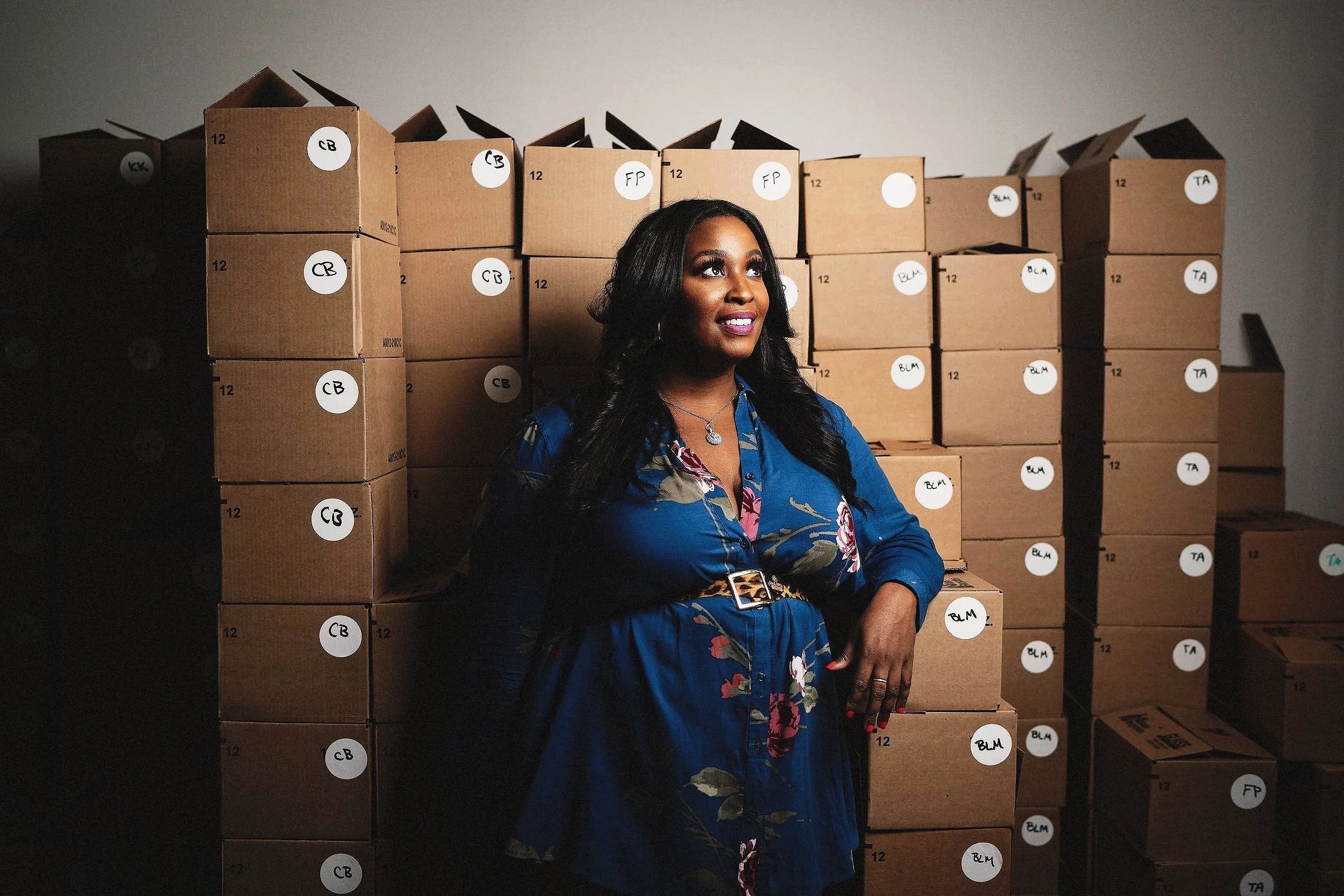 Environmental portrait of Alesia Miller, founder of Soul Brew Kombucha, standing in front of stacked product boxes.