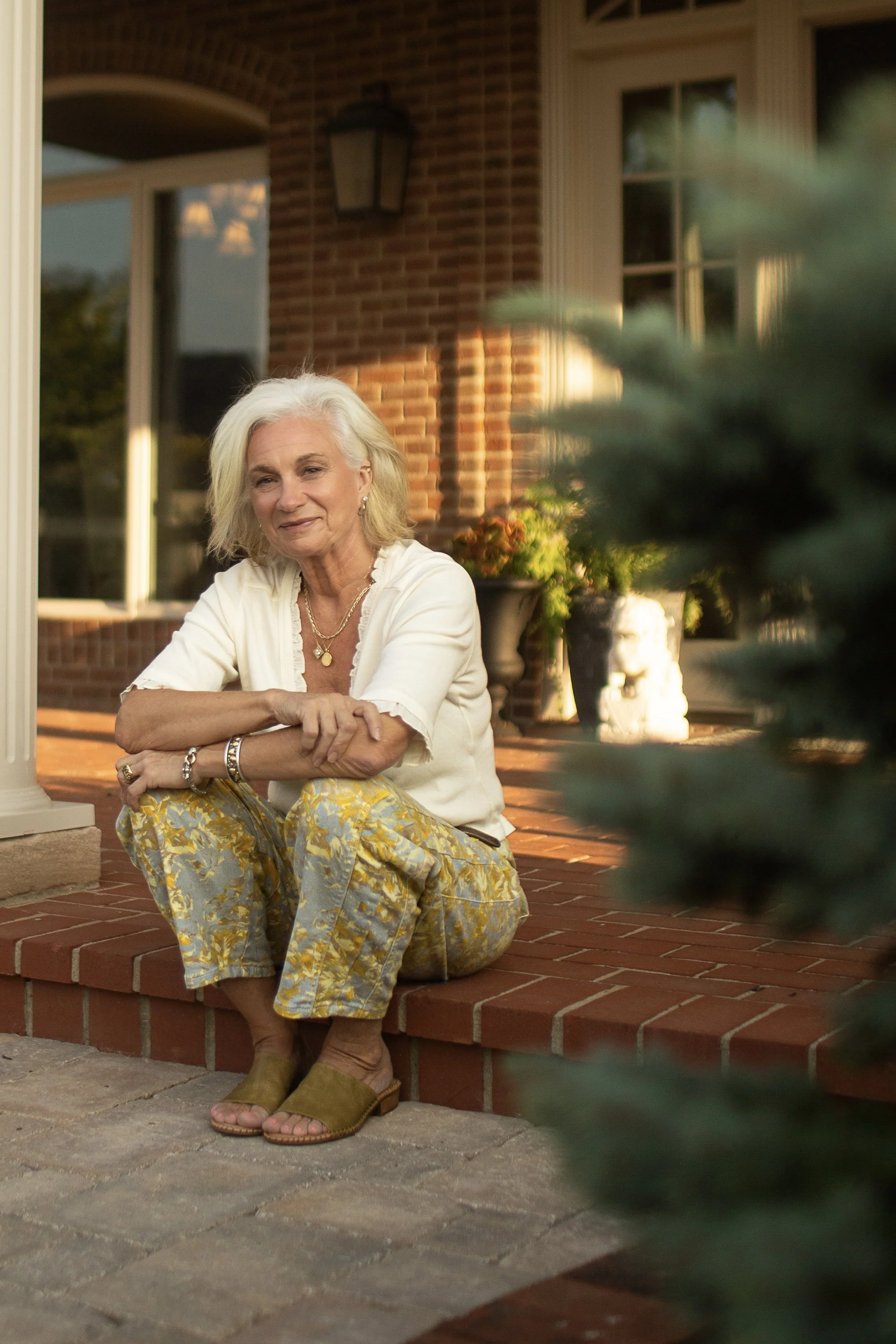 A headshot of artist Diana Paxton sitting on her front porch