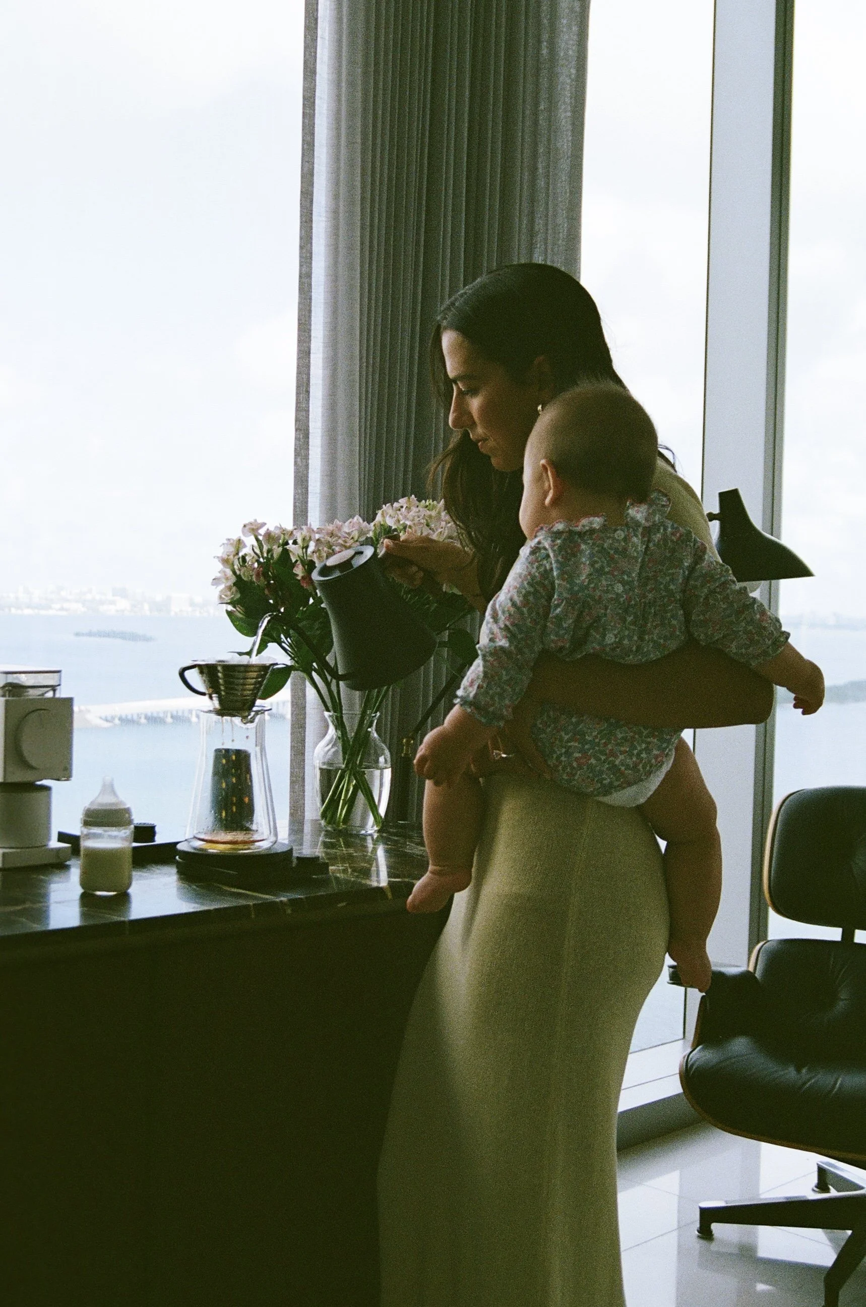 NYC mom enjoying coffee pour over and baby on her hip