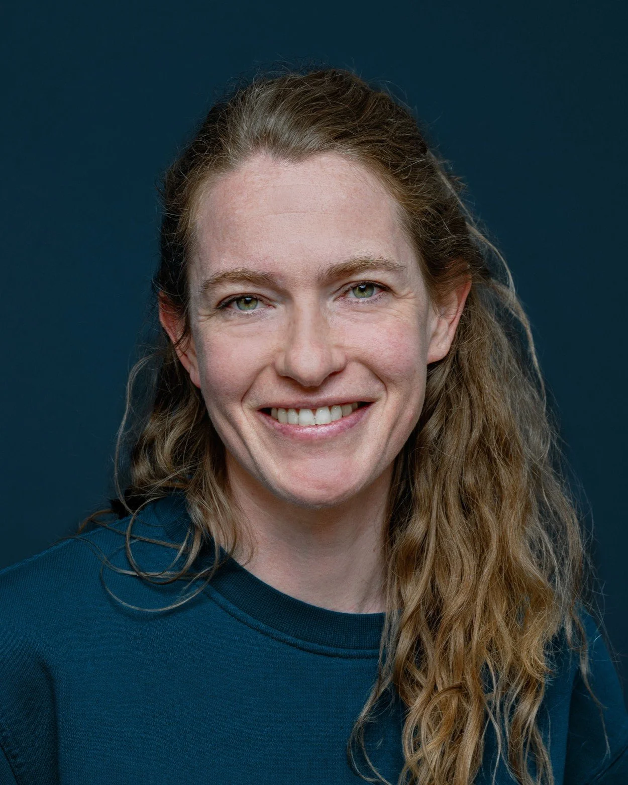 Portrait einer lächelnden Frau mit langen Haaren vor einem dunklen Hintergrund