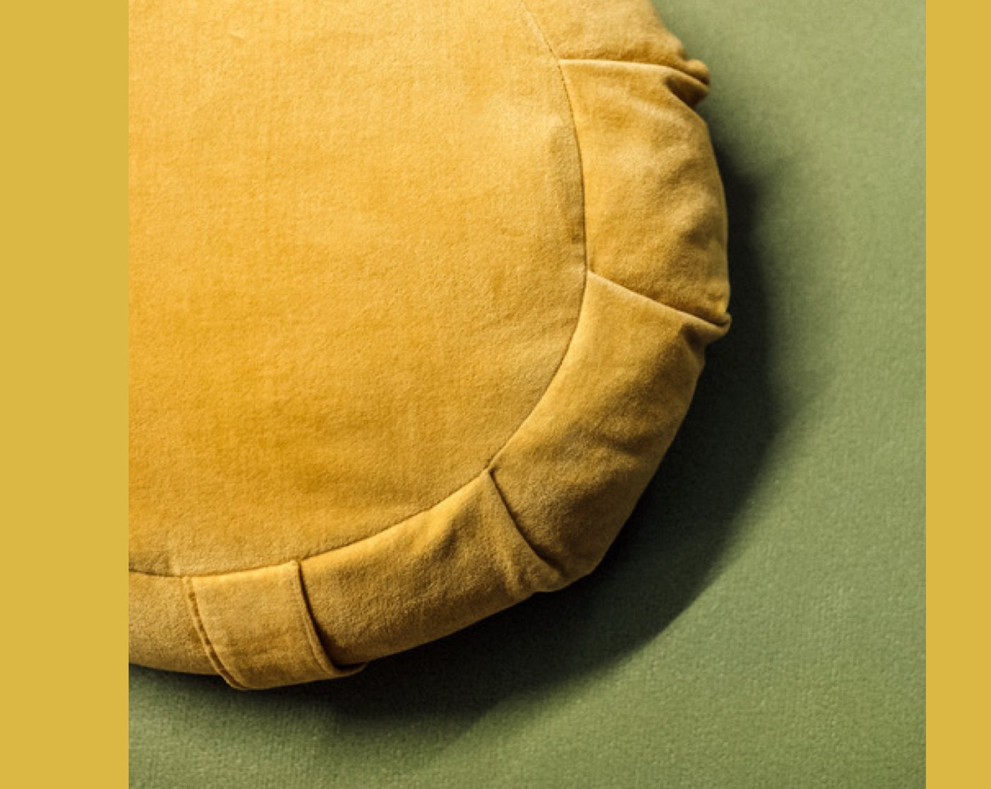 Ein gelbes Meditationskissen, das auf einer grünen Matte liegt.