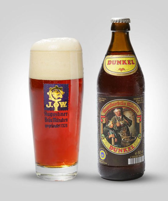 A glass of dark beer with a foamy head next to a brown beer bottle labeled 'Dunkel' from Chiemseer Bräu.