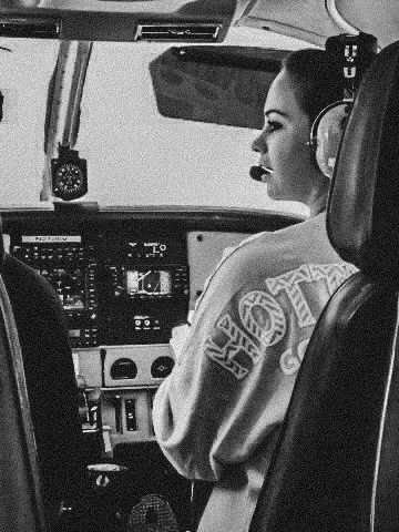 Black and white image of a side profile of a woman flying a plane