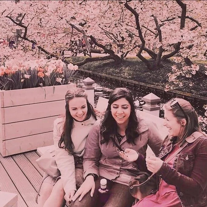 Pink filtered photo of three women laughing on a bench