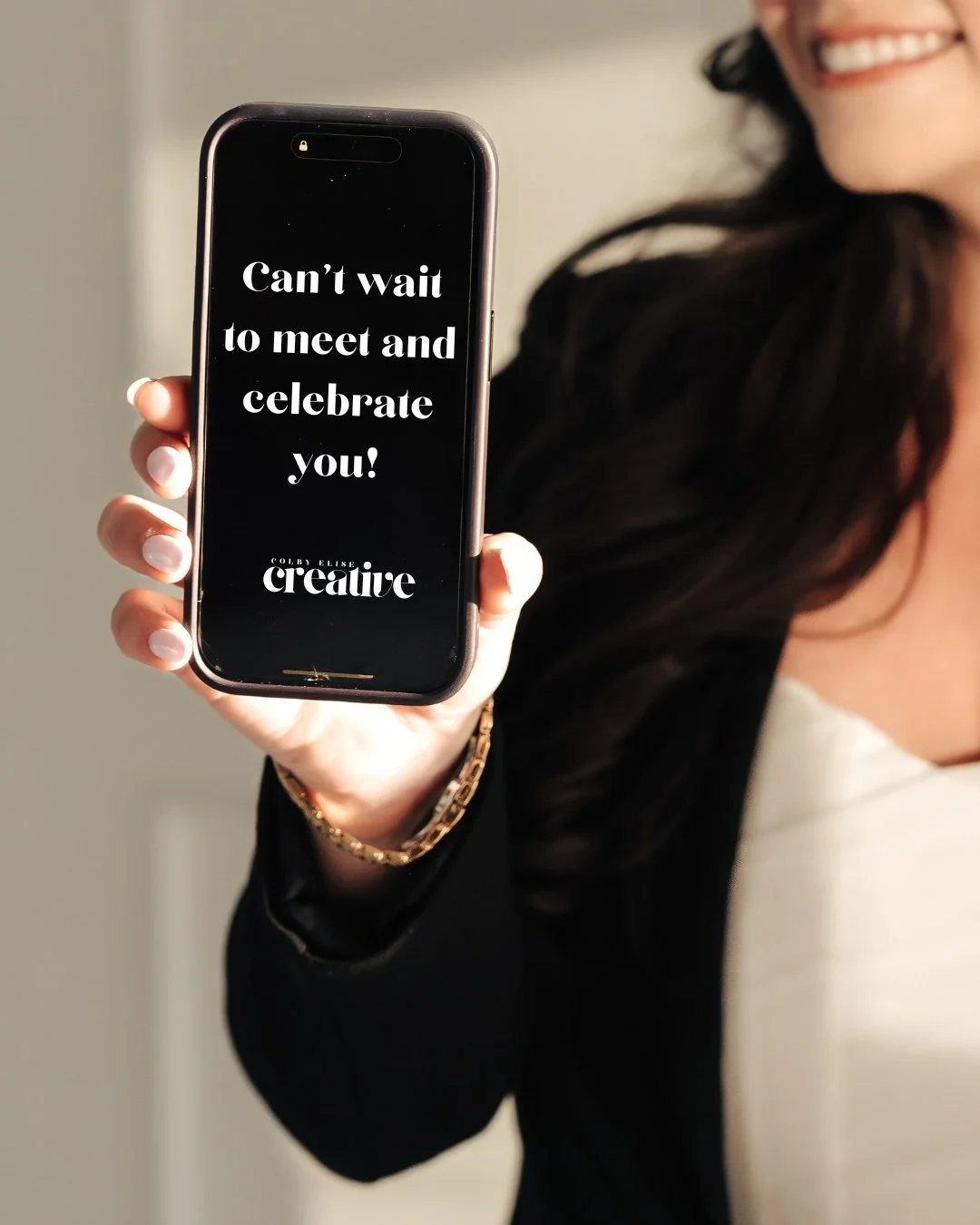Photo of a woman holding a phone. Text on the phone screen states, "Can't wait to meet and celebrate you!"
