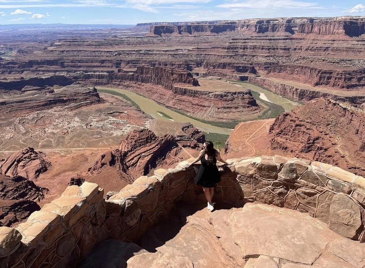 Woman in black dress leans against a ledge in Utah