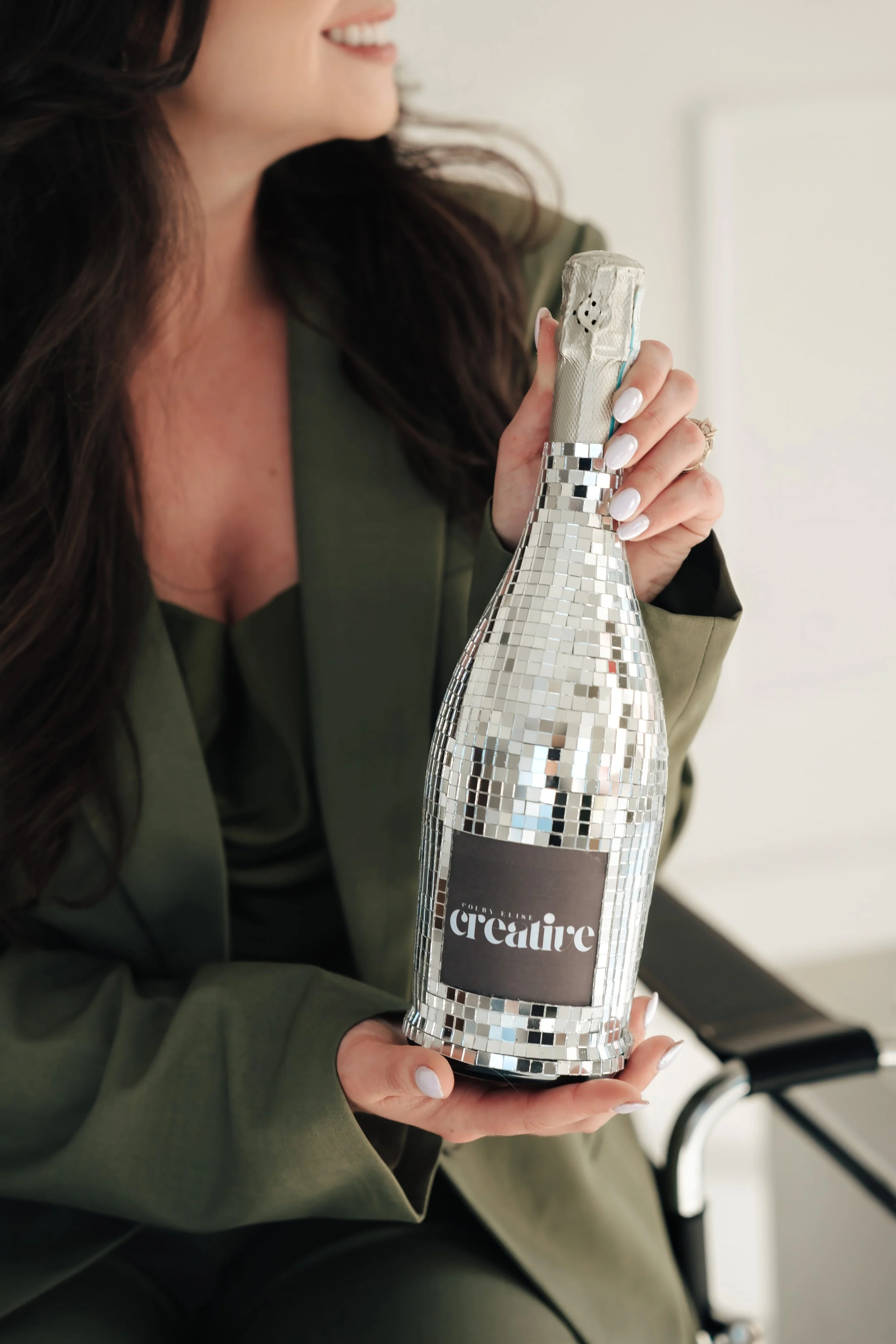 Woman hold champagne bottle decorated with disco tiles