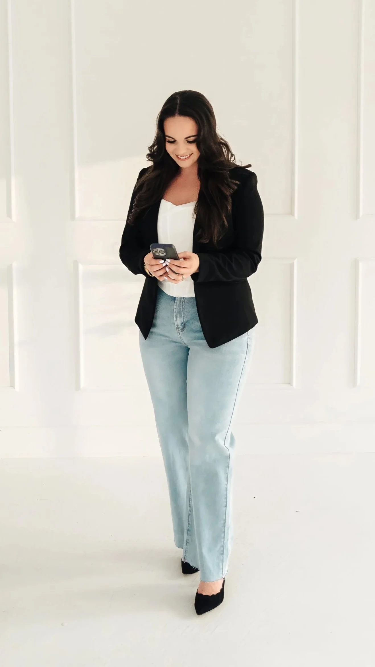 Woman standing and looking down at her cell phone