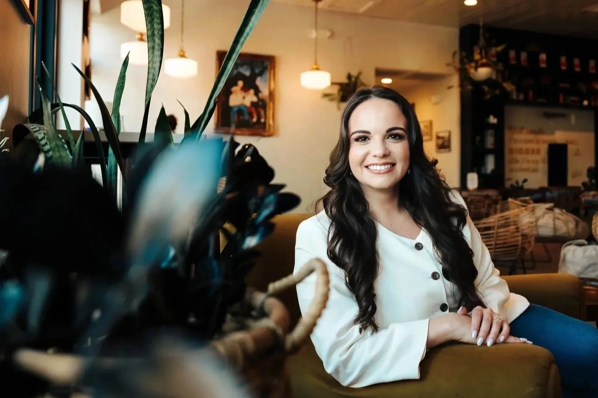 Woman smiling in coffeeshop next to plant