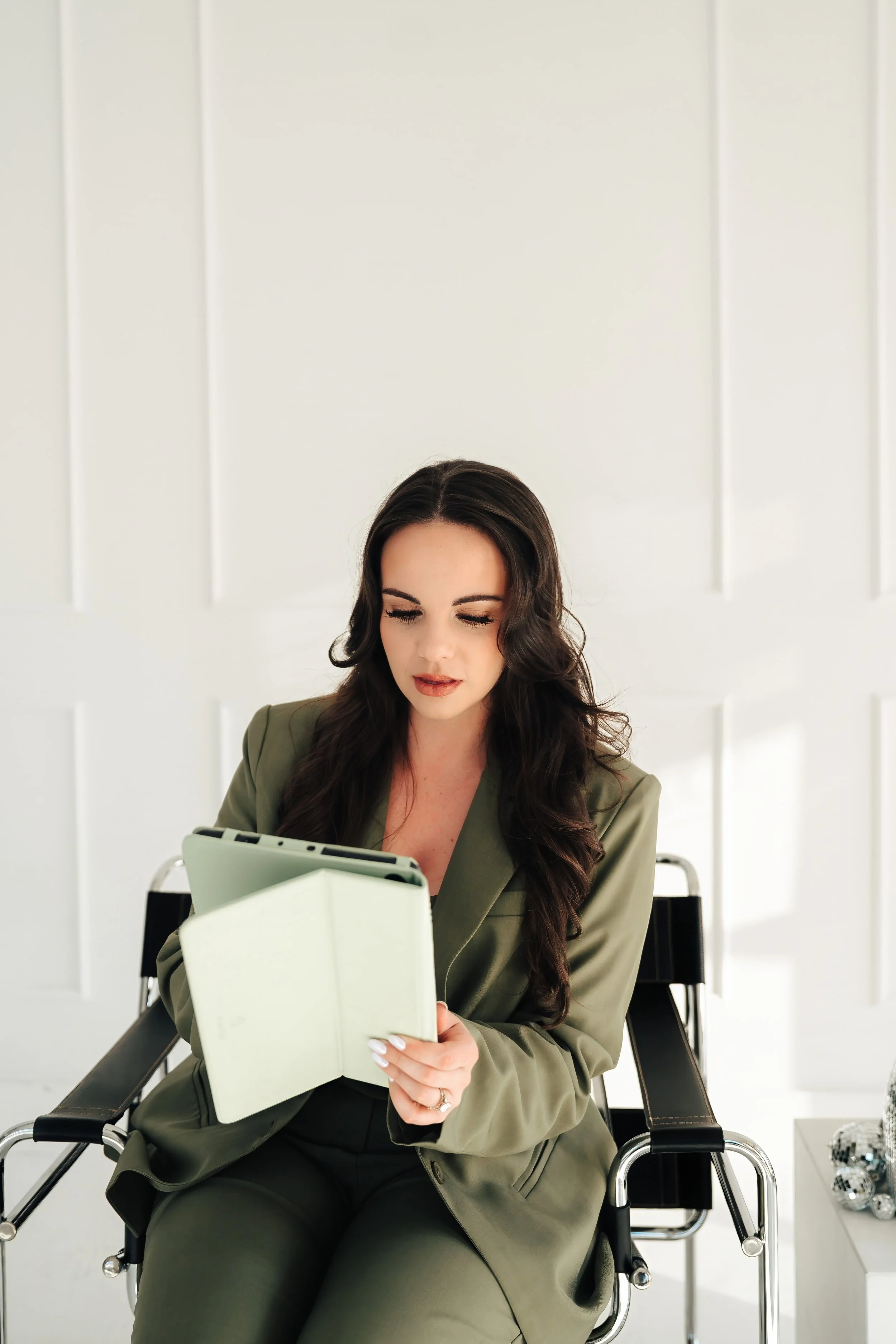 Woman in green suit looks down at a tablet