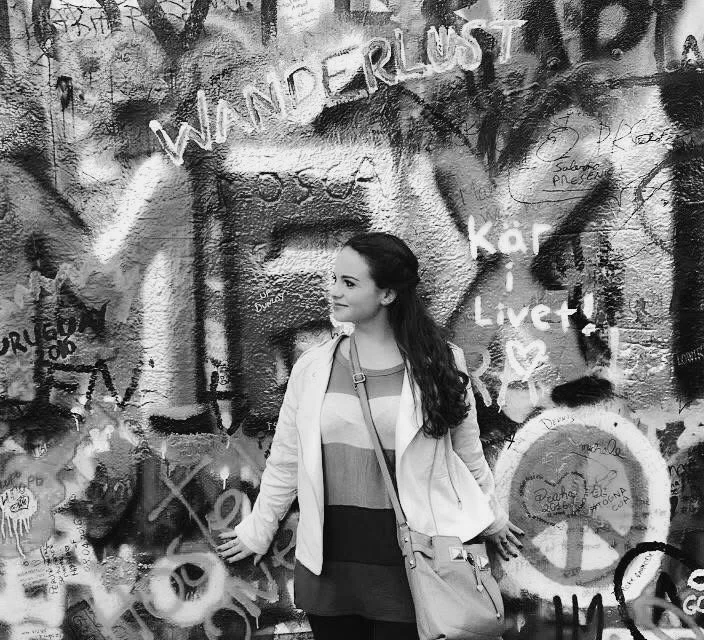 Woman leaning against the John Lennon wall in Prague