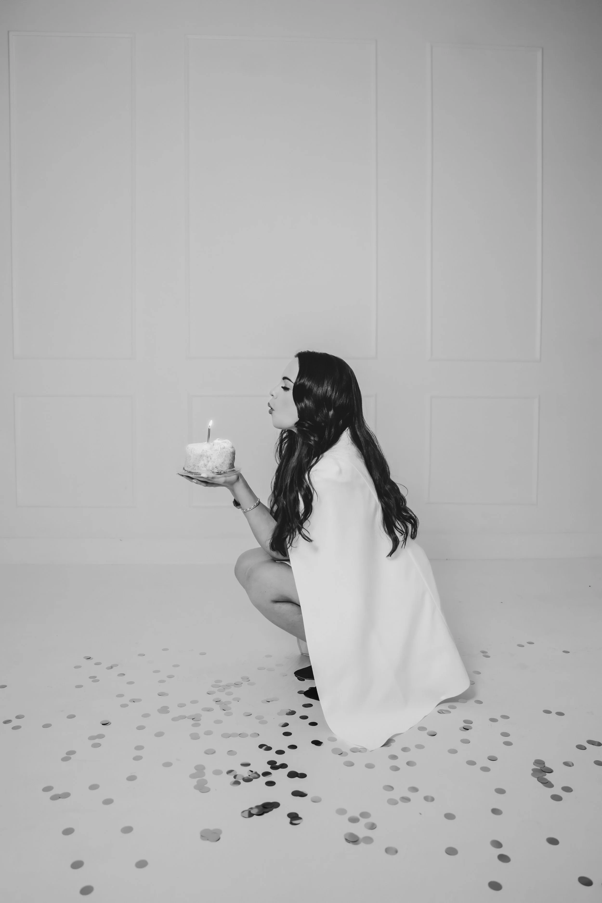 Woman in white cape blowing out candle on birthday cake