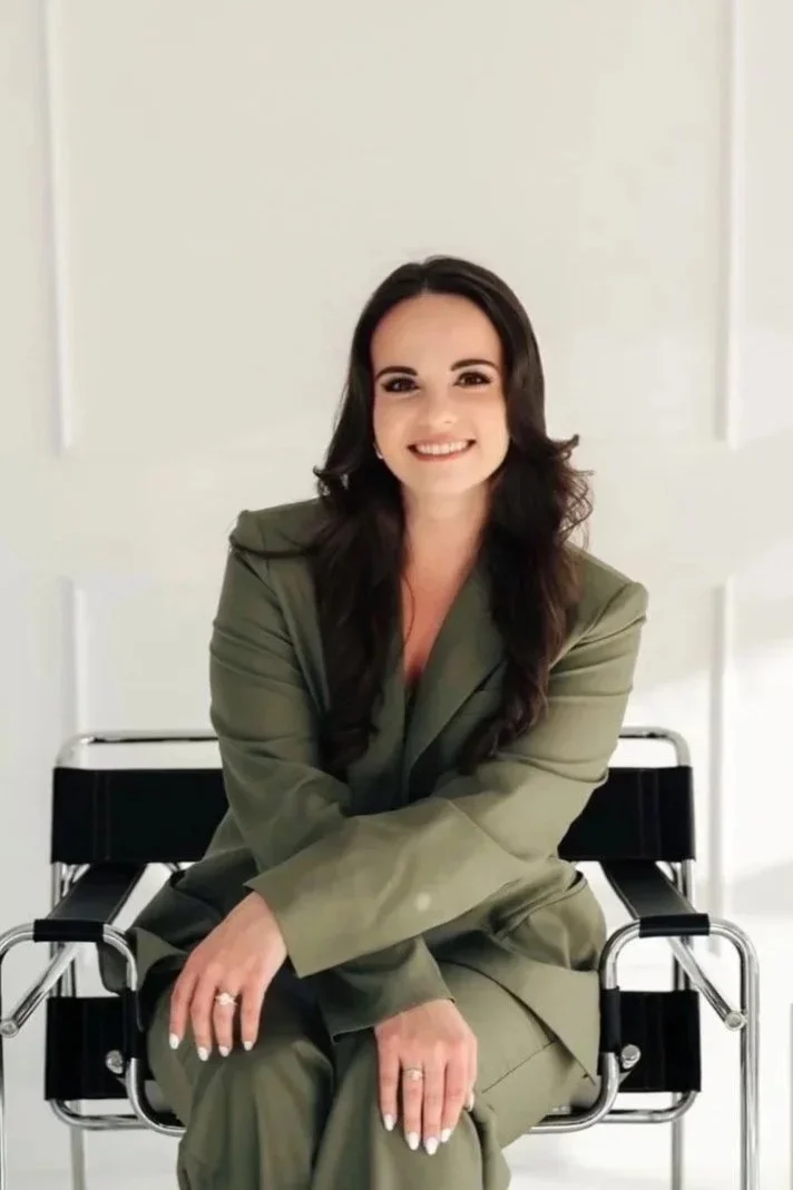 Business woman sitting in chair wearing green suit