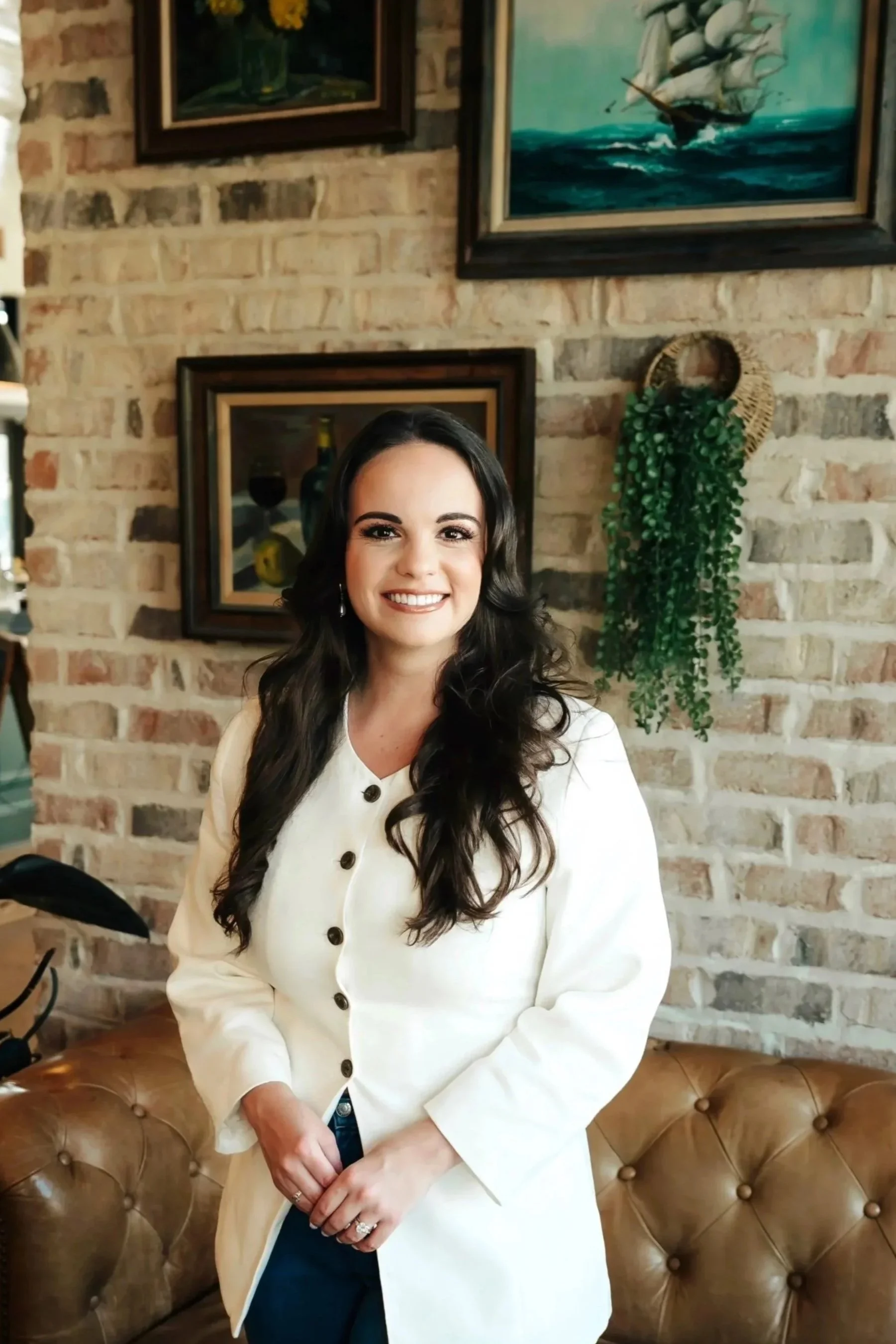 Portrait of woman in white jacket in front of a brick wall