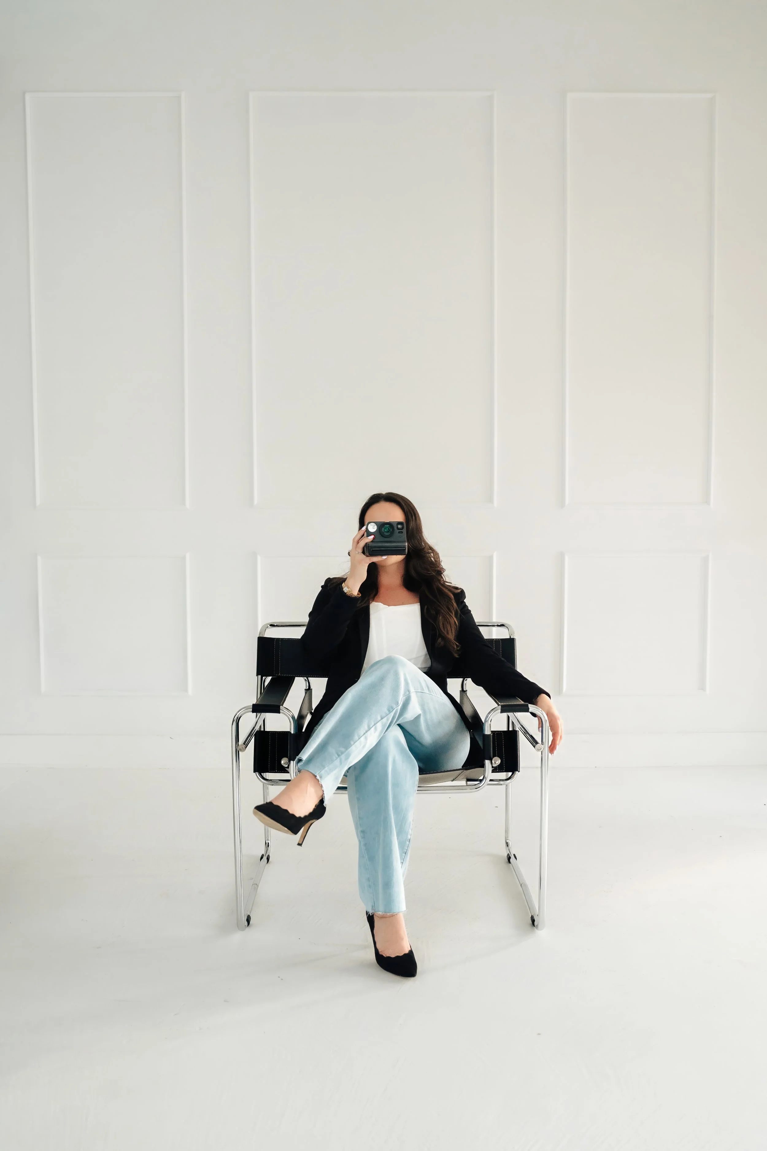 Woman sitting in black chair holding a polaroid camera