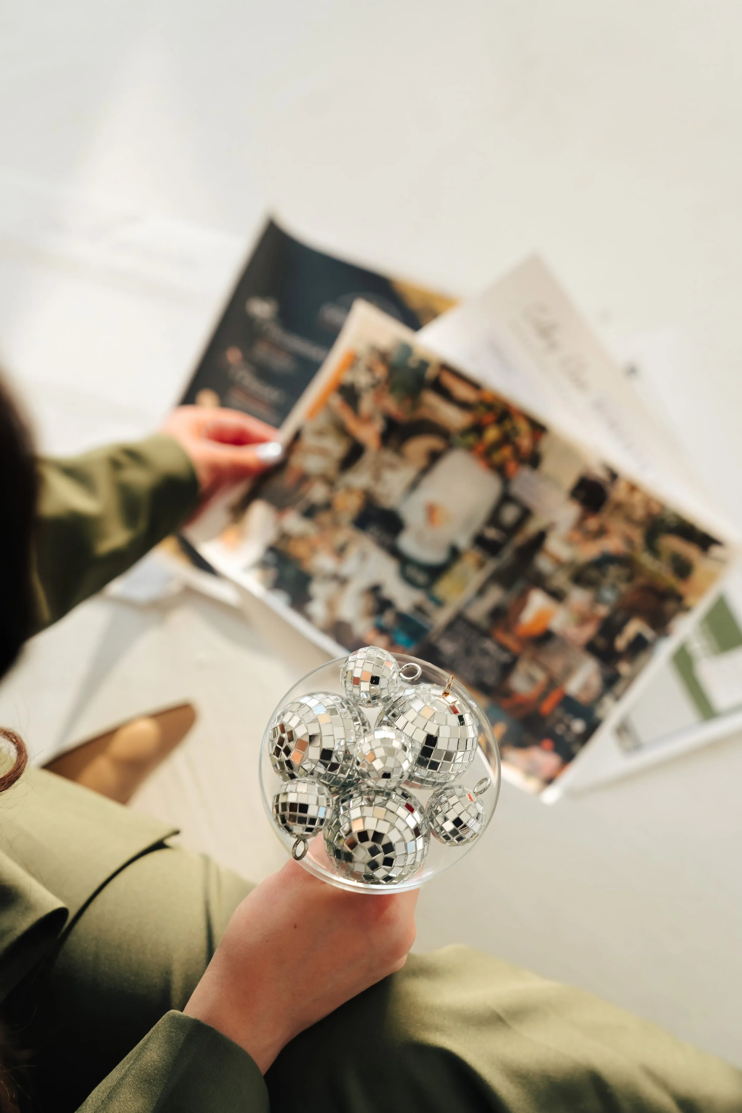 Woman holds champagne glass with disco balls in front of colorful papers