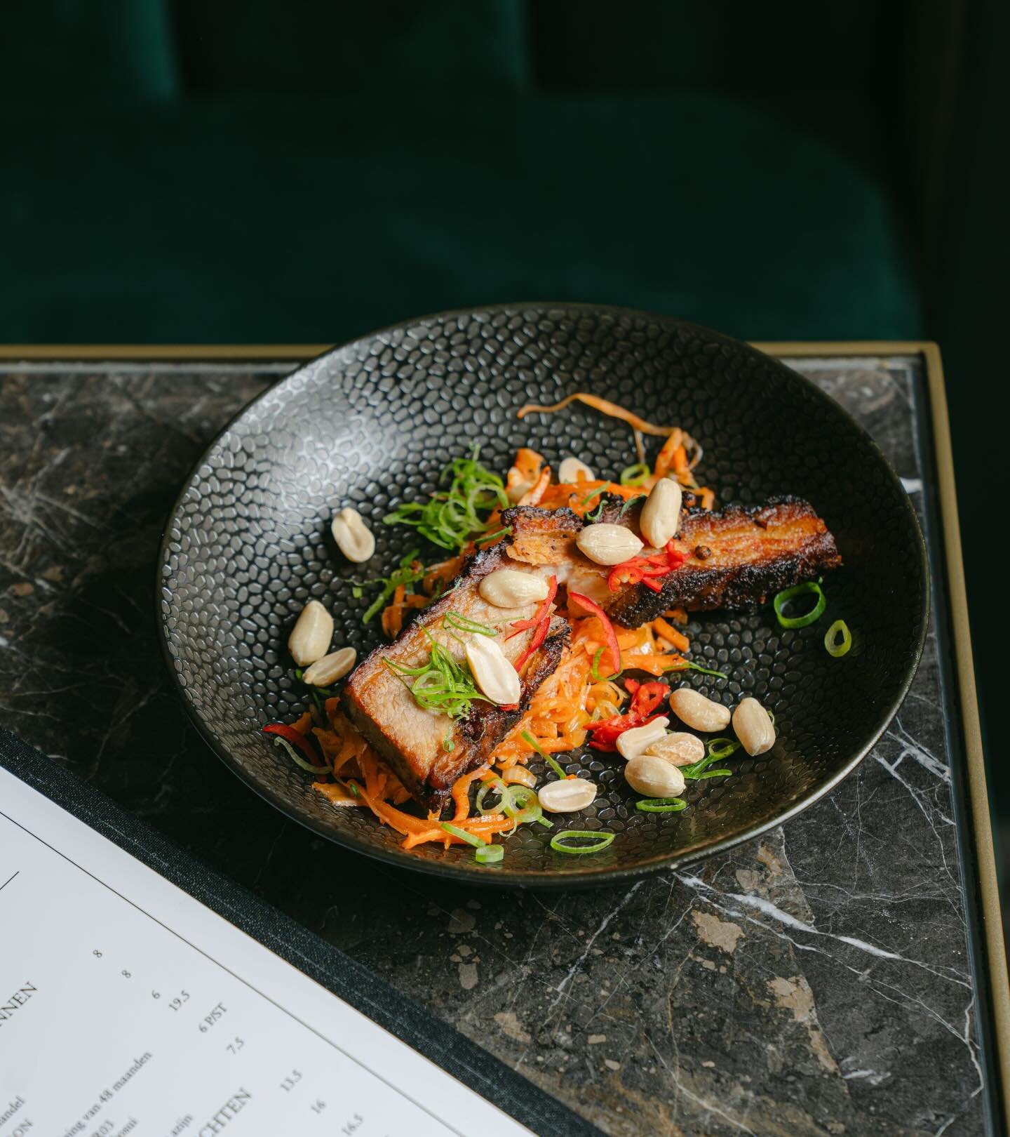 Heerlijk knapperige buikspek op een bedje van kimchi, met lente-ui, pinda&rsquo;s en rode peper voor extra pit! 🌶️

De perfecte balans tussen hartig, zuur en spicy zorgt voor een smaakexplosie bij elke hap. 🌟

Wanneer kom jij de buikspek proberen? 