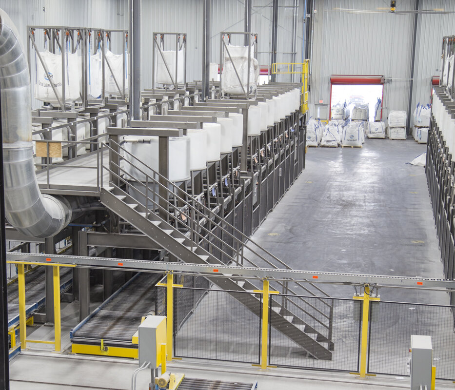 The system features two identical batching line configurations consisting of rotationally-molded polyethylene dispensing hoppers.