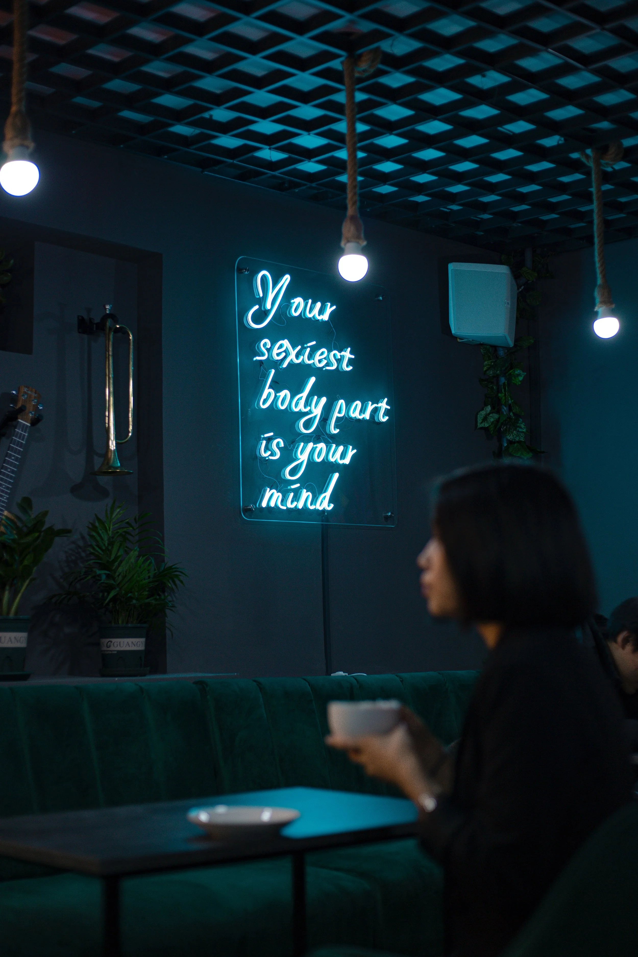 Neon sign reading “Your sexiest body part is your mind” in a dim lounge, reinforcing sex and mental health and introducing the difference between orgasm and climax as mind–body experiences.