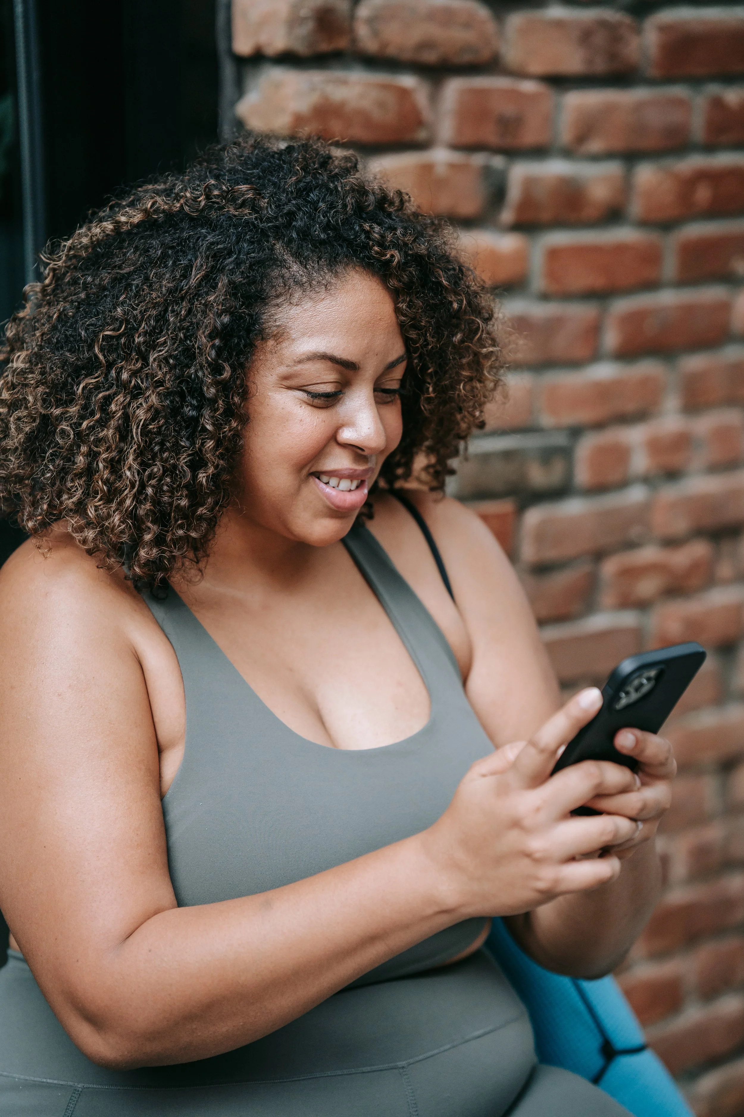 Woman smiling while using a smartphone outdoors, representing the benefits of brain training and simple daily habits for how to train your brain.