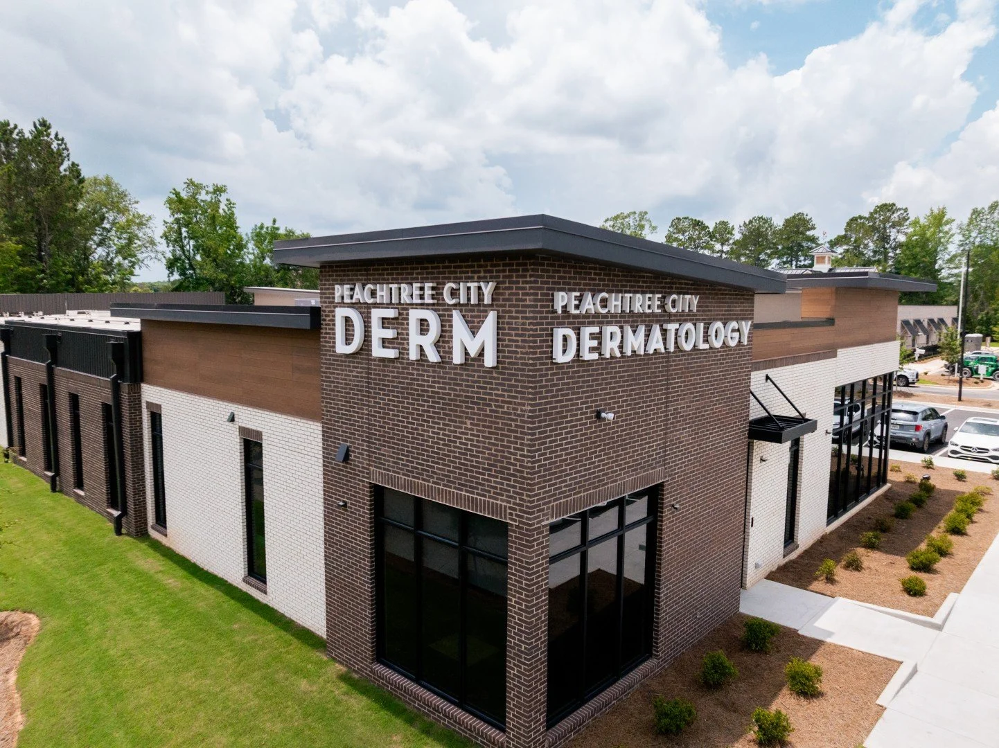Exterior of Peachtree City Dermatology clinic building with brick and white siding, large windows, and signage on the corner