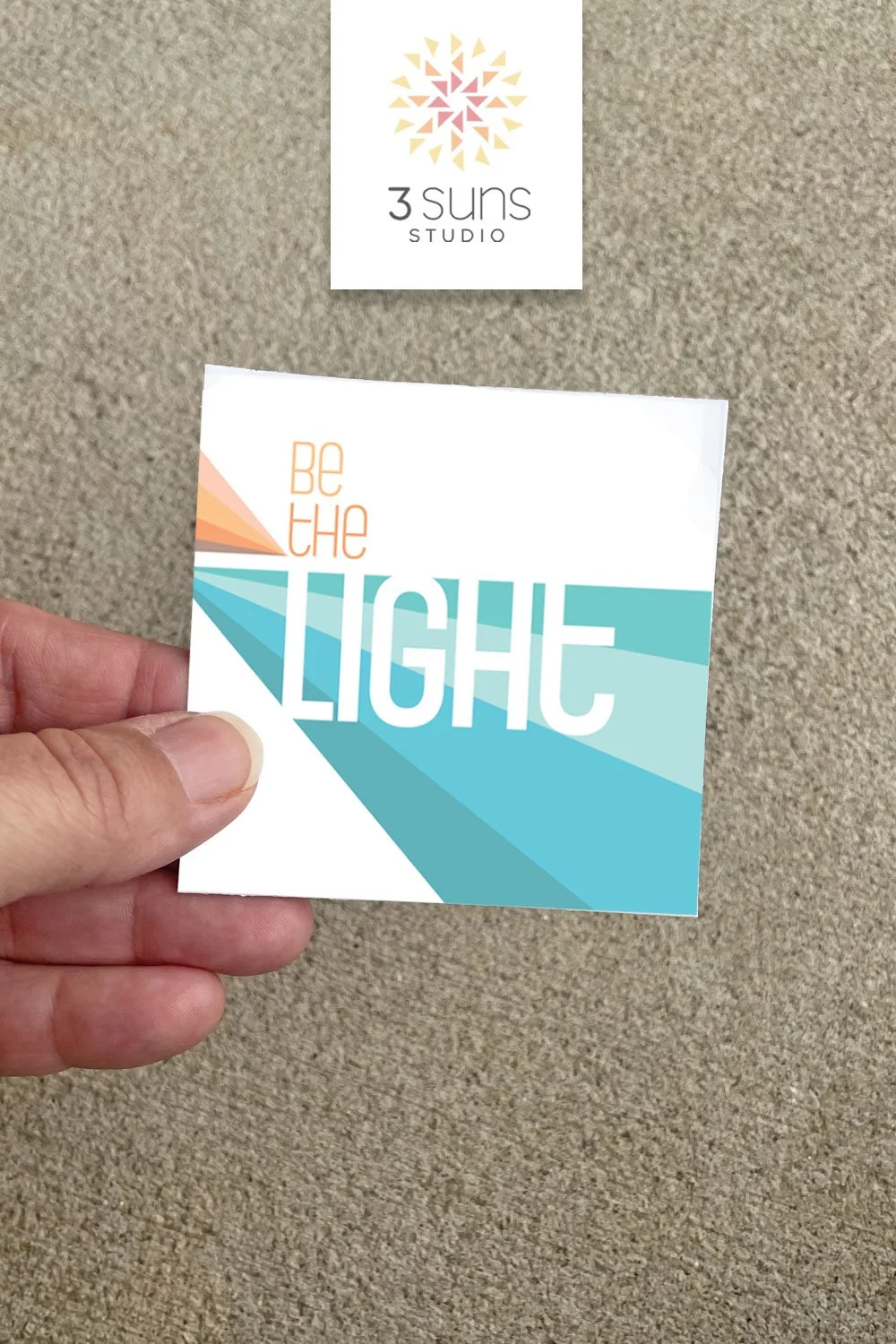 A clean and simply designed sticker depicting the inspirational quote “be the light”. Colors include orange and peach along with blue and green.