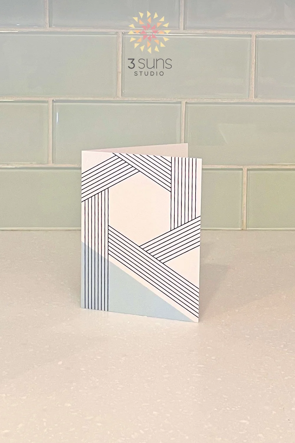 A linear abstract notecard featuring interlocking pattern black parallel lines with a pop of color anchoring the corner.