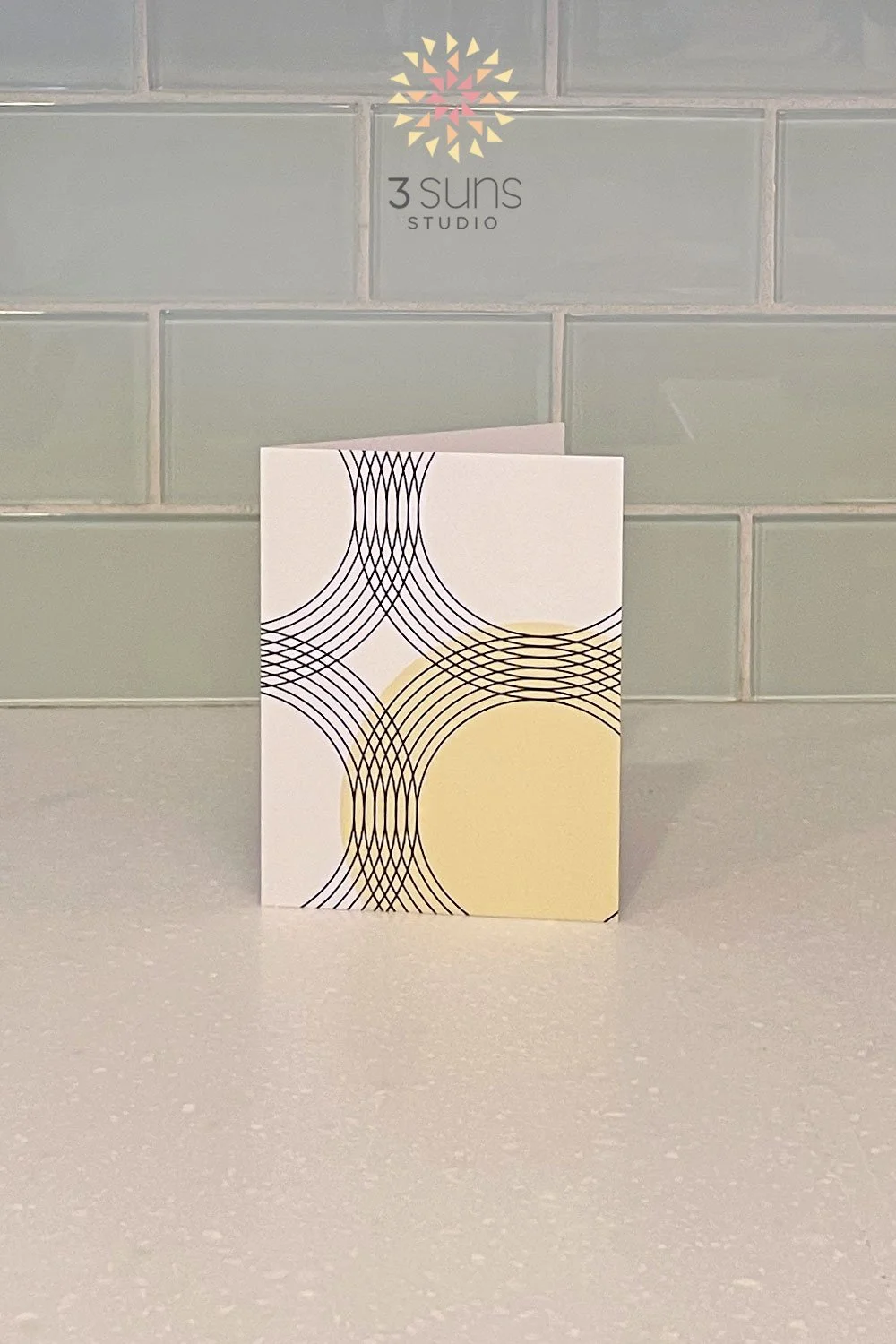 A linear abstract notecard featuring graceful curves and circular intersections and a neutral black and white palette with a pop of color.