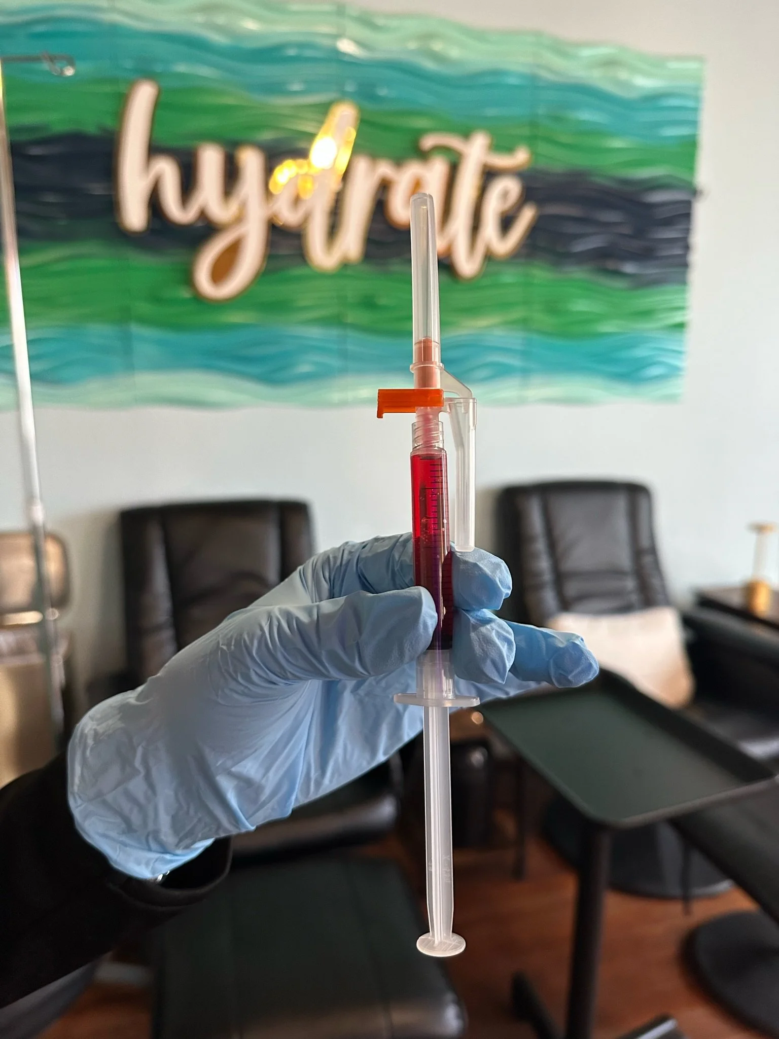 Registered Nurse holding vitamin injection in front of hydrate sign in The Irenic Place Infuse Room in Aledo, Texas