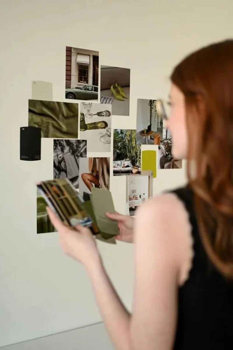 Woman reviewing images on phone near vision board, representing what is brand strategy and visual brand planning