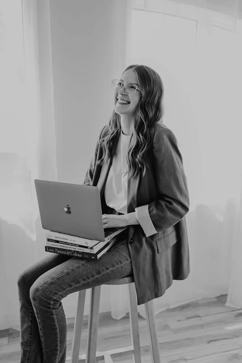 Smiling designer working on laptop, representing web design in Edmonton, creative, professional and approachable brand experience.