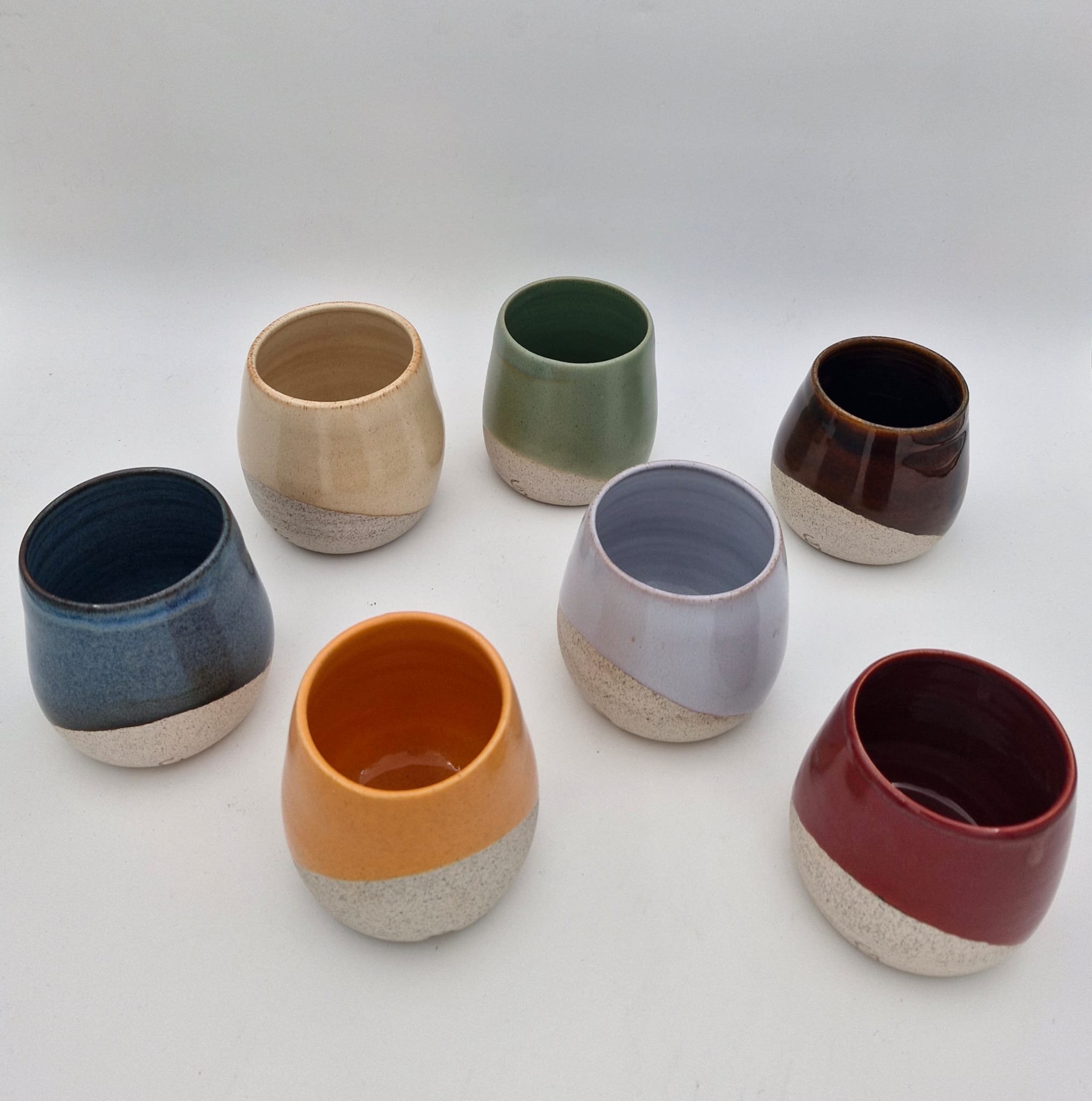 Three ceramic vases in varying sizes and shapes on a wooden surface against a light-colored wall.