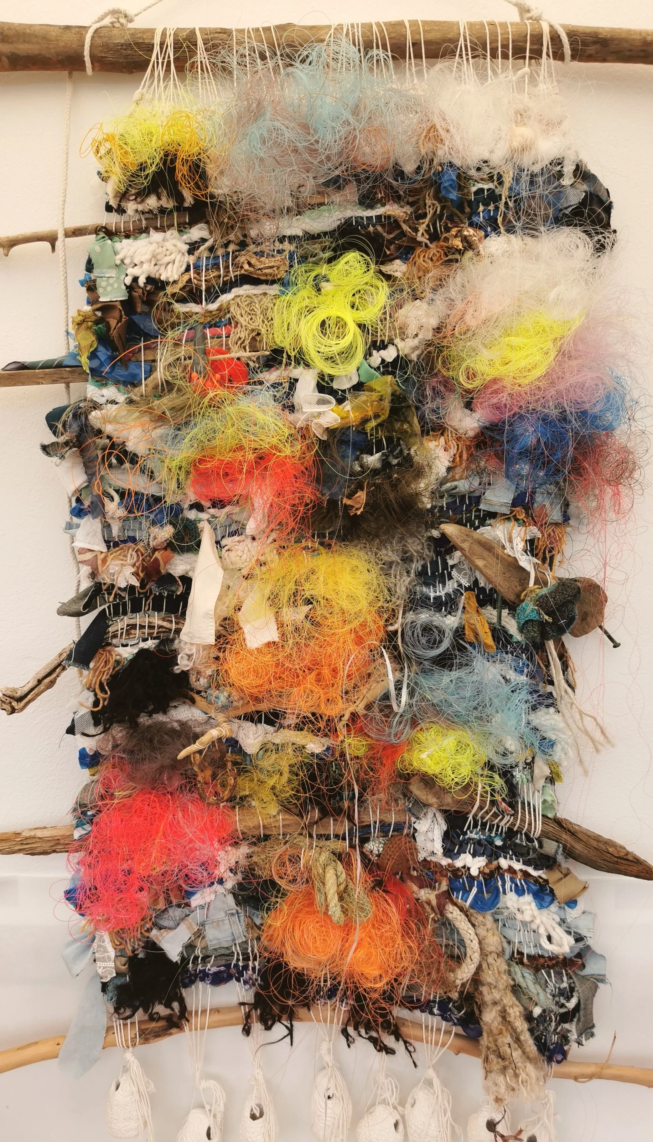 'Weaving Migrants' A year long research into the artists ancestors, from ancient royalty  to the Huguenot weavers. 
Image: Plastic Reef. Woven recycled fabric scraps, yarn, monofilament fishing line and found object, ceramic loom weights.