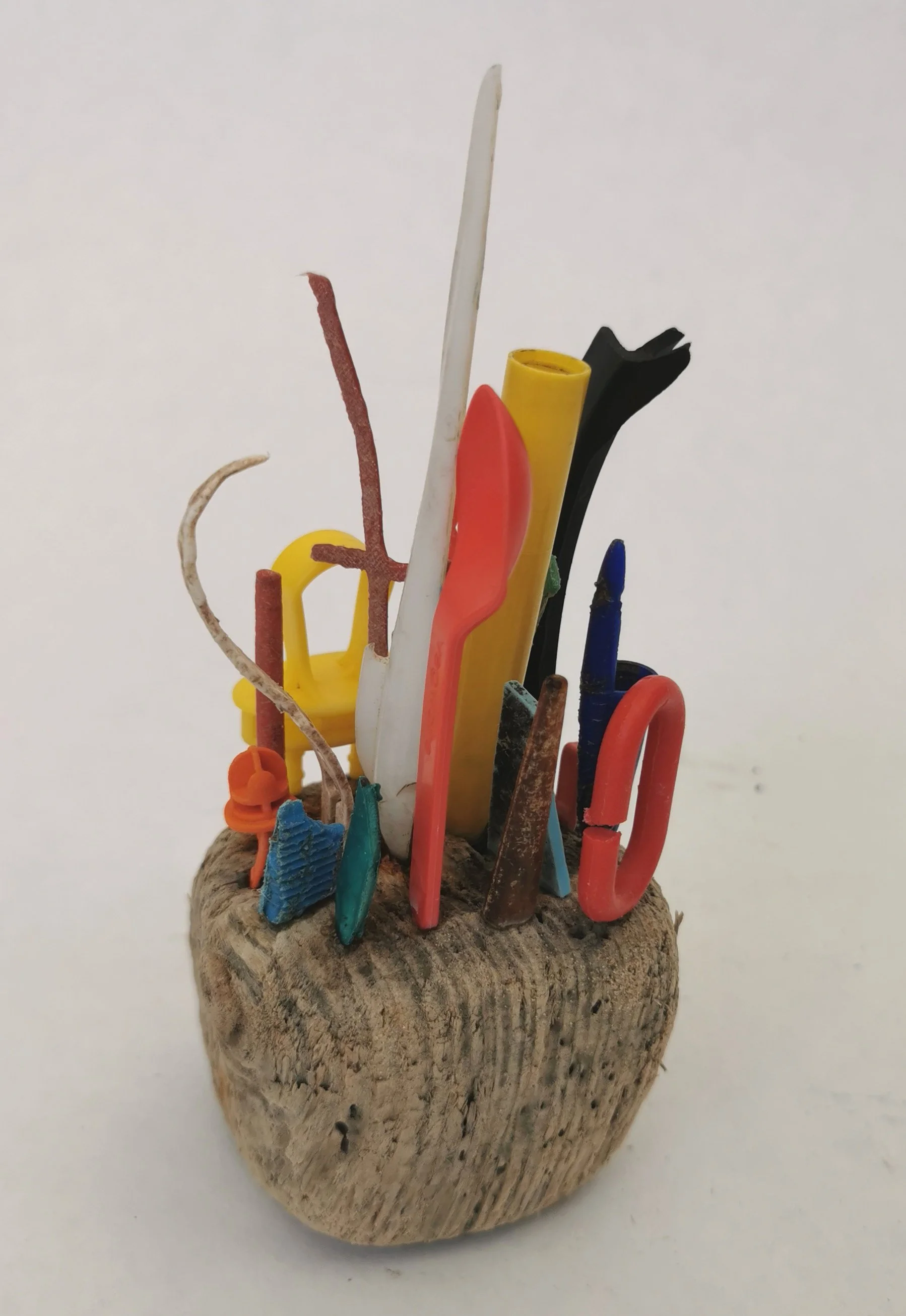 'Plastic Islands' Collected microplastic pieces assembled into miniature high rise cities perched precariously on driftwood islands, a comment on marine plastic and coastal erosion.