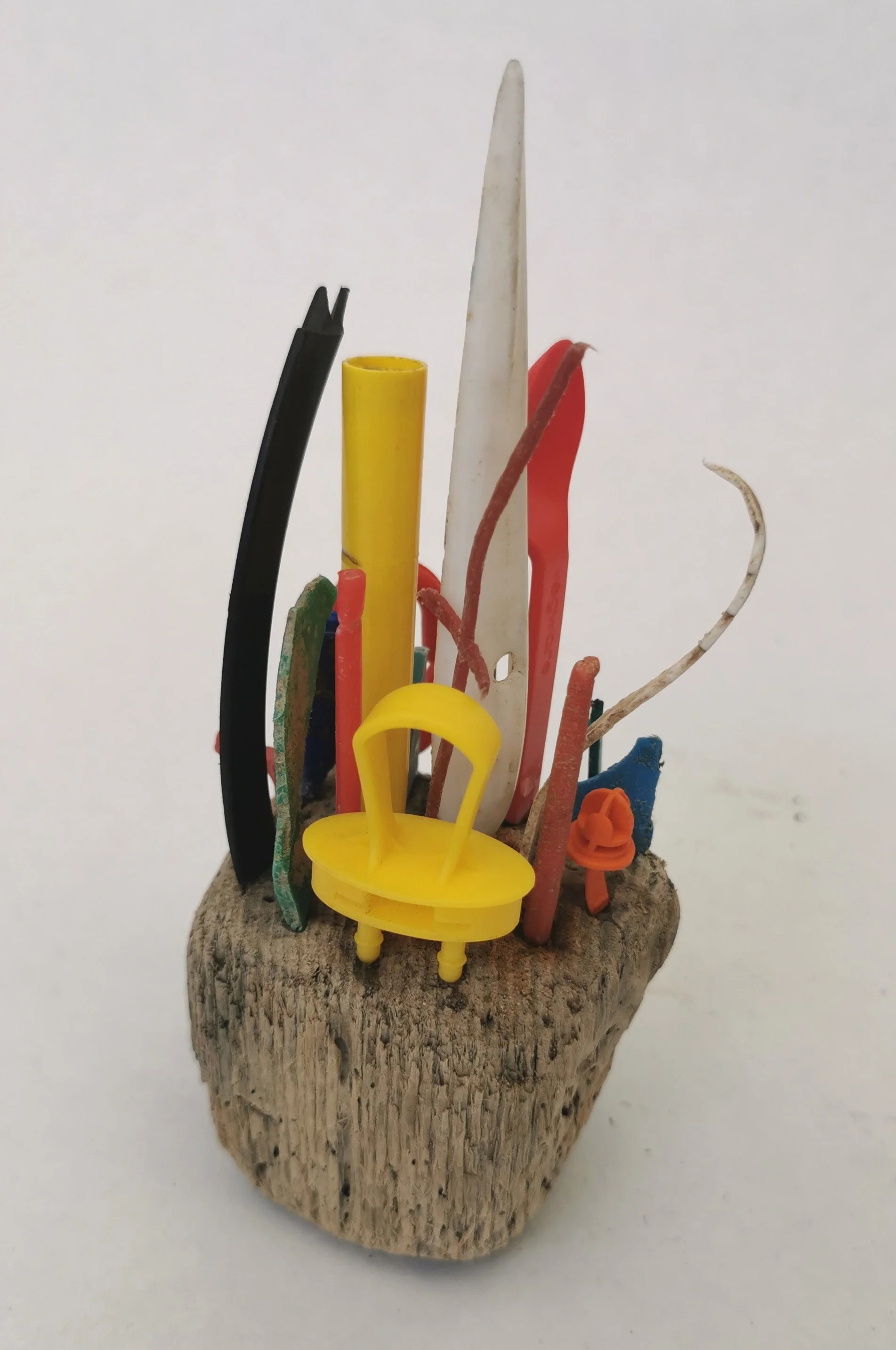 'Plastic Islands' Collected microplastic pieces assembled into miniature high rise cities perched precariously on driftwood islands, a comment on marine plastic and coastal erosion.