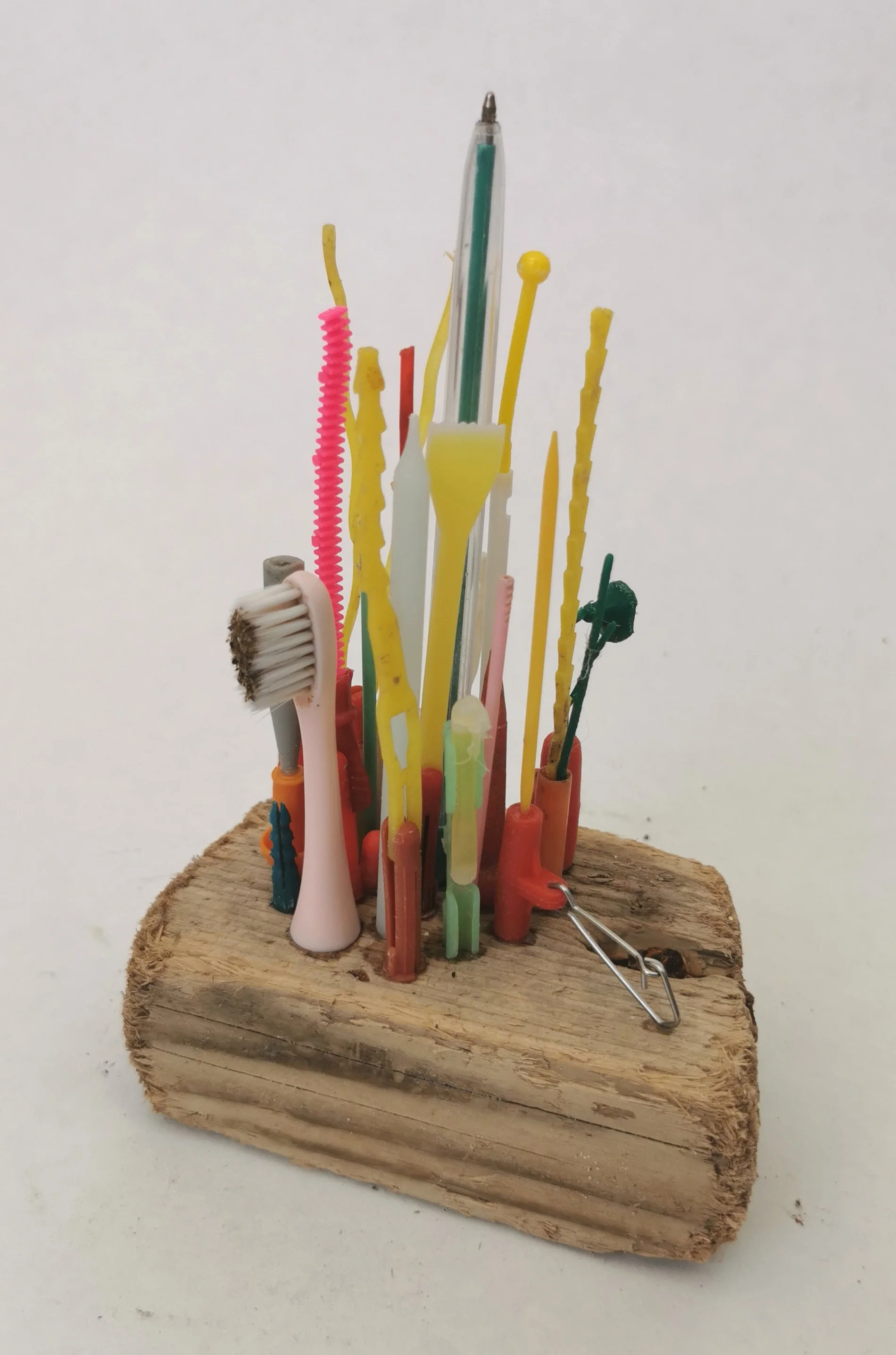 'Plastic Islands' Collected microplastic pieces assembled into miniature high rise cities perched precariously on driftwood islands, a comment on marine plastic and coastal erosion.