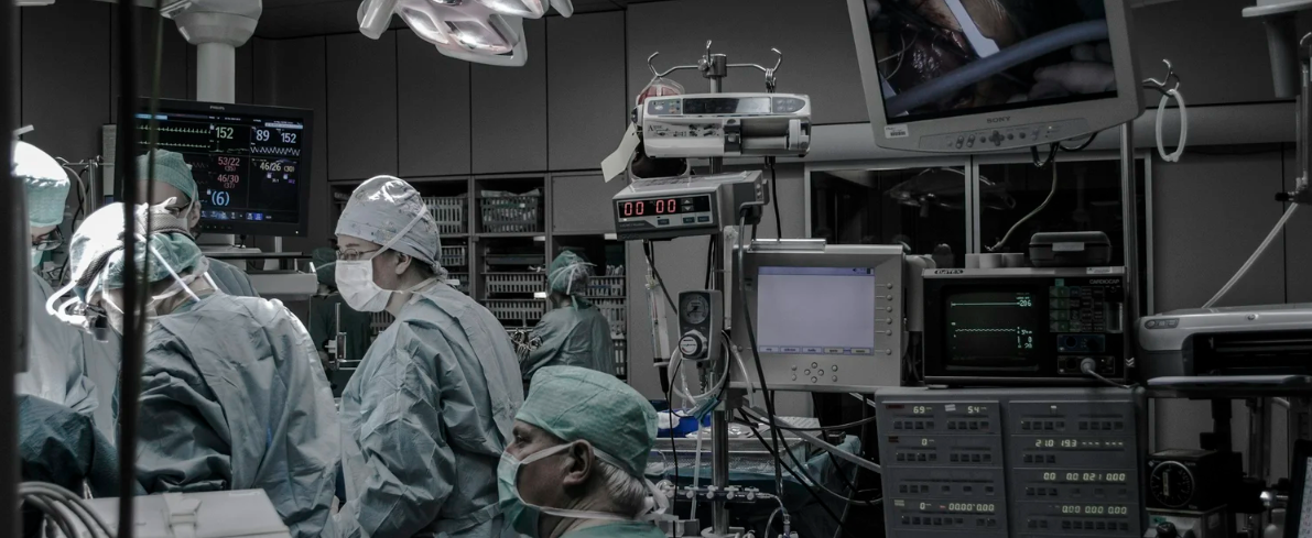 Medical professionals performing surgery in an operating room with monitors and medical equipment.