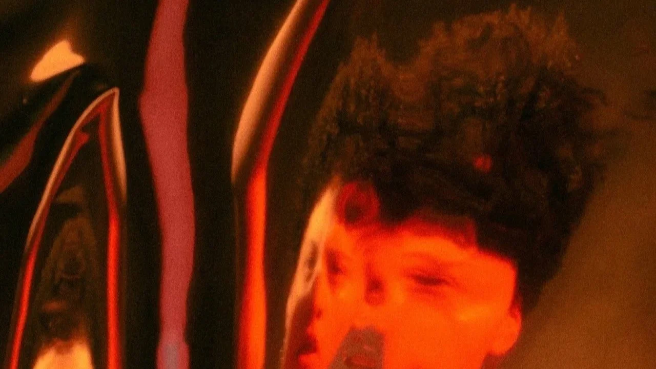 distorted artsy photo of a woman's face and arms with orange lighting