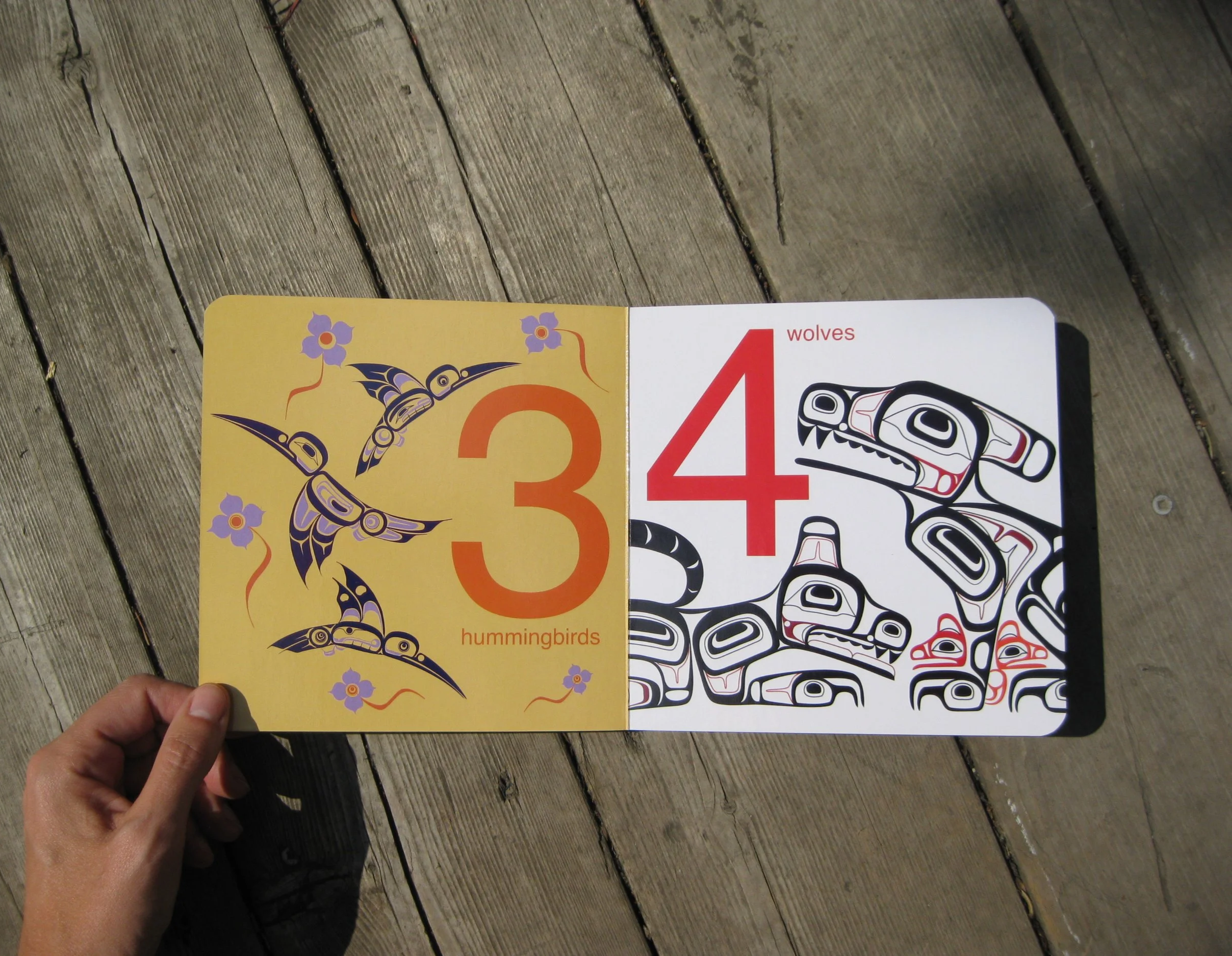 Kids board book with first nations art showing 3 hummingbirds and 4 wolves